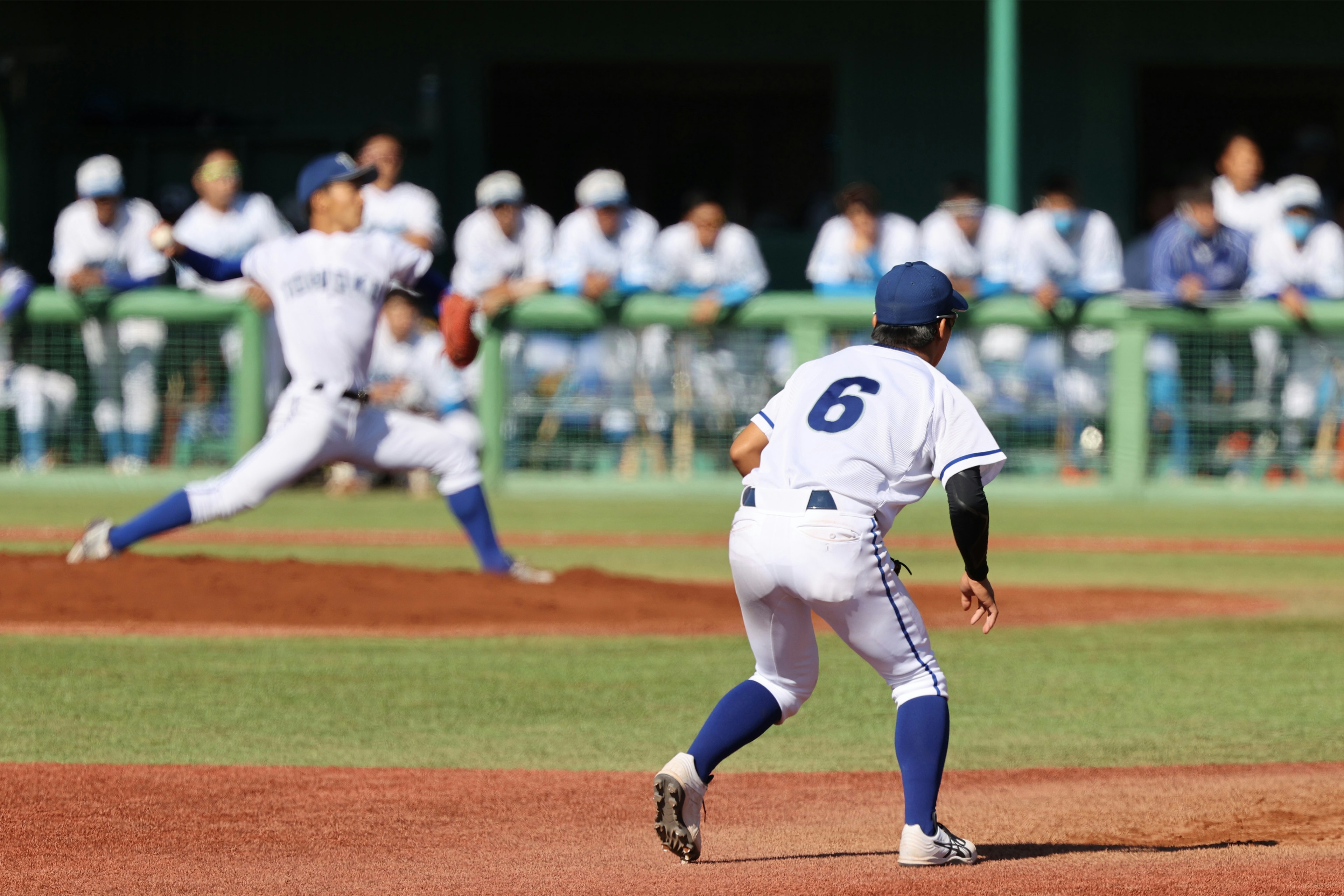 Baseballspiel mit Pitcher, der den Ball wirft, und einem Baseman, der vorankommt