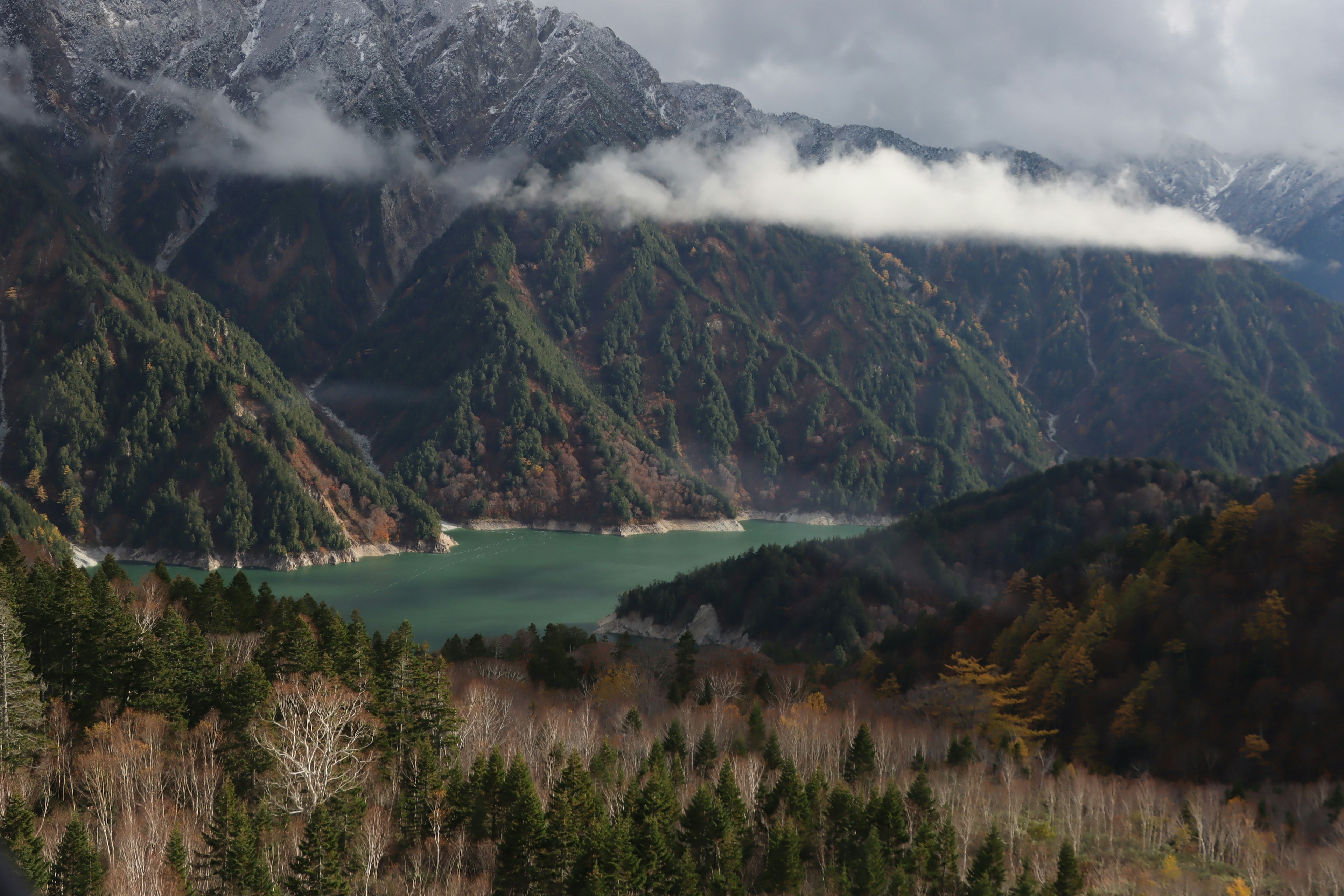 Scenic view of a blue lake surrounded by majestic mountains and clouds