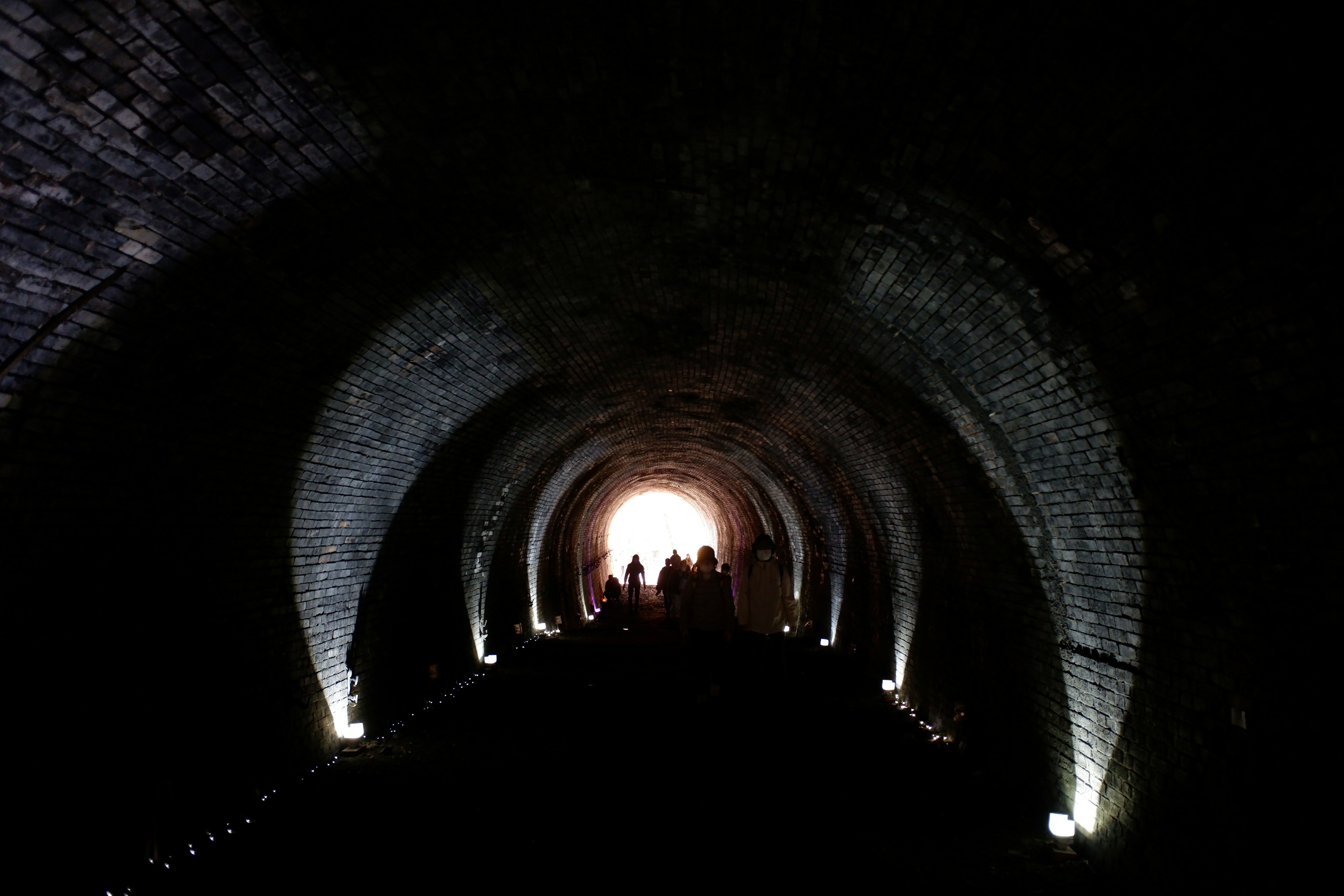 Un tunnel sombre avec une lumière brillante à l'extrémité et des silhouettes de personnes