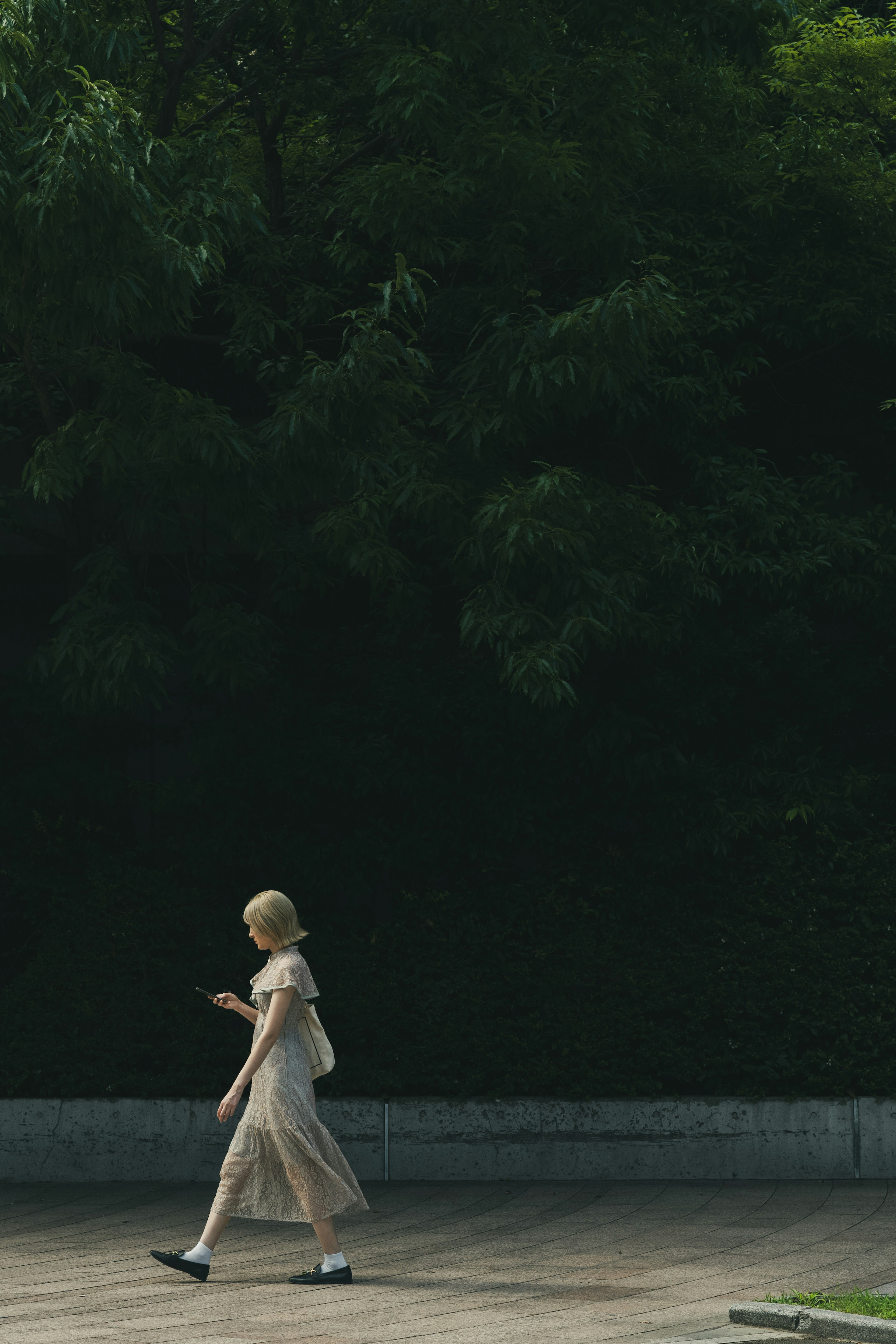 Une femme blonde marchant devant un fond vert