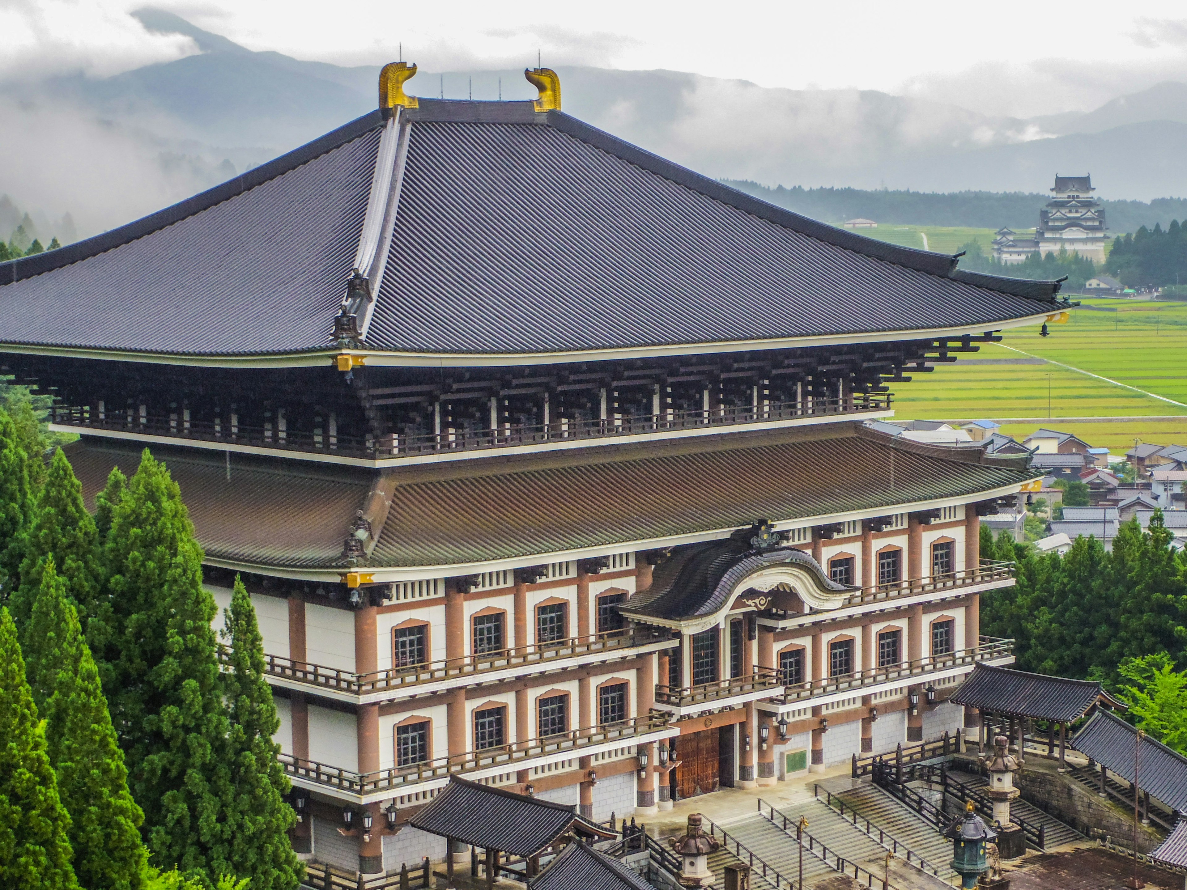 美しい日本の寺院の外観で屋根が特徴的で周囲に緑が広がる