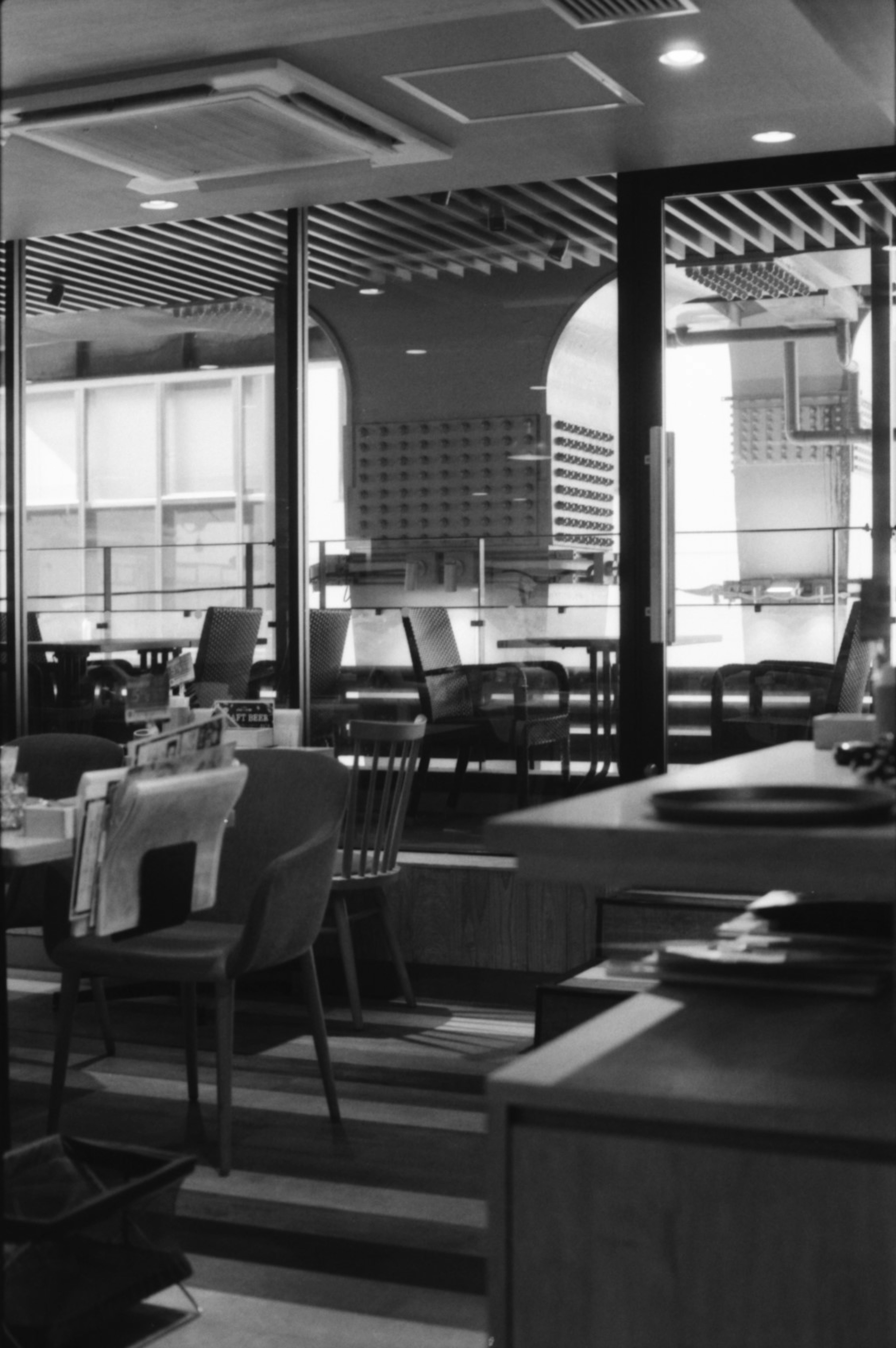 Interior de una cafetería moderna con grandes ventanales y sillas y mesas ordenadas