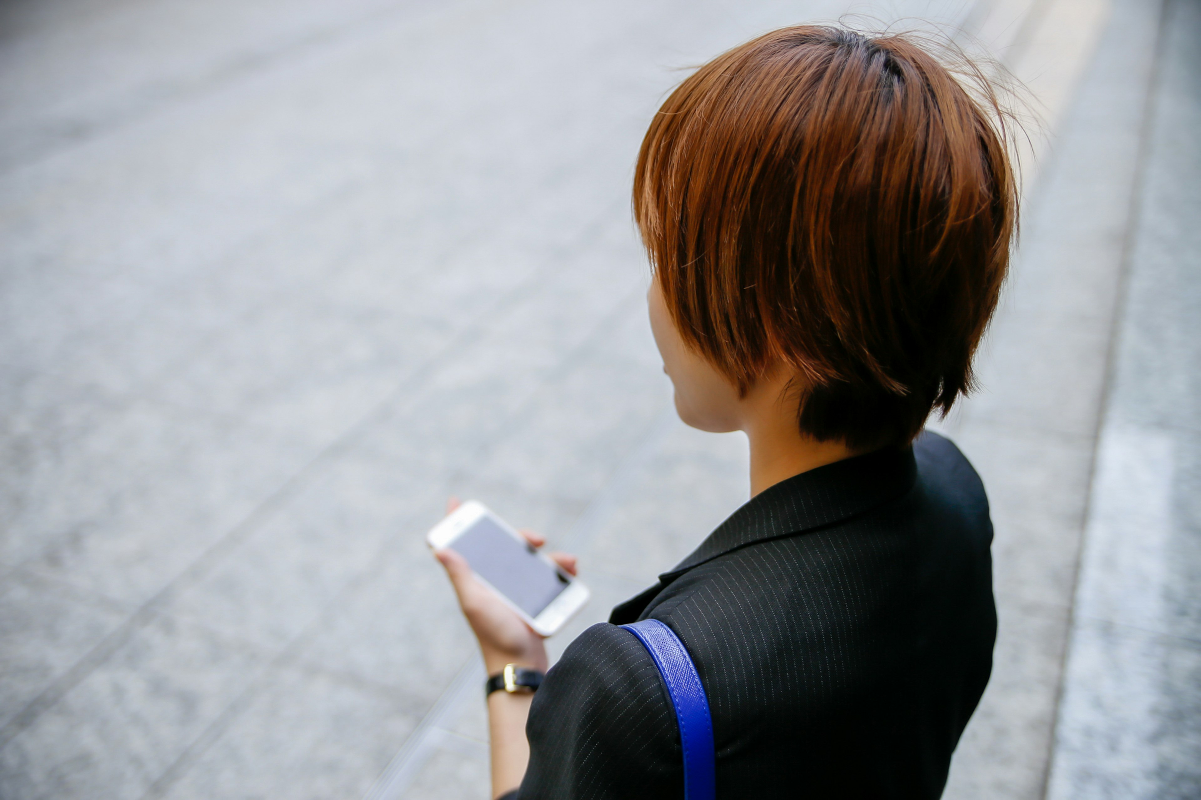 A woman holding a smartphone seen from behind