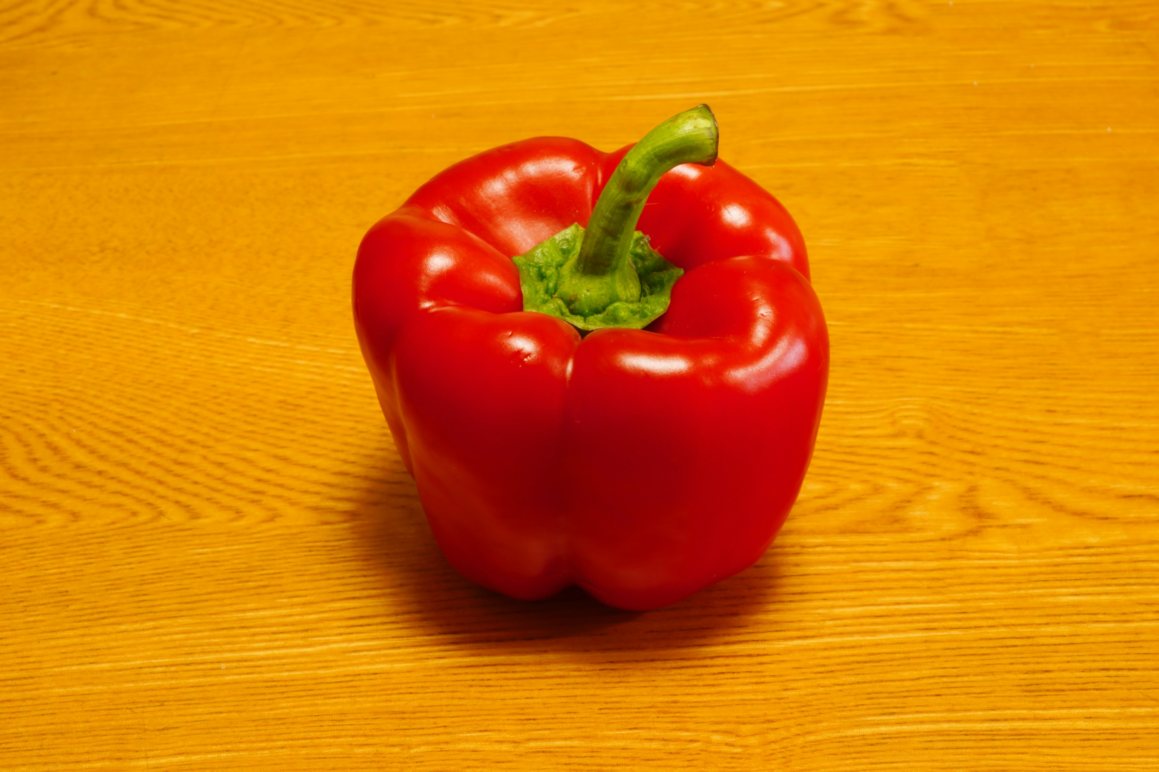 Red bell pepper placed on a wooden table