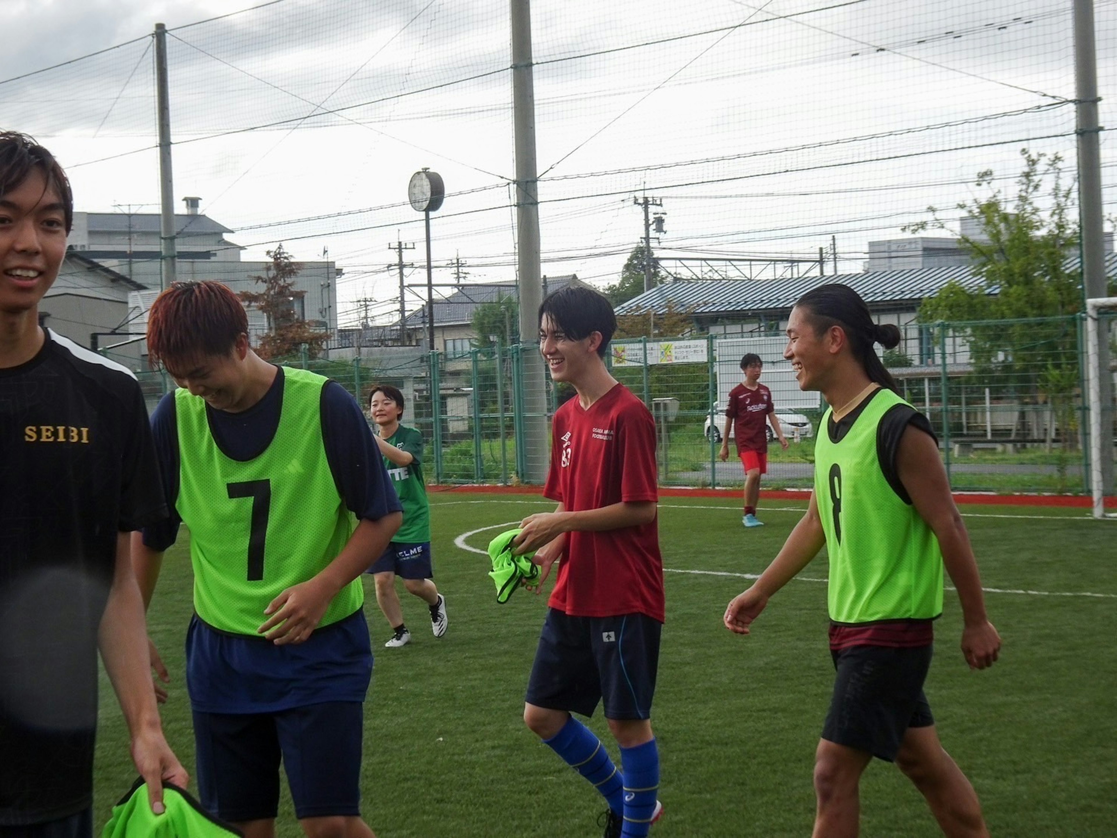 축구 연습 중인 젊은 선수들이 웃으며 녹색 조끼를 입고 있다