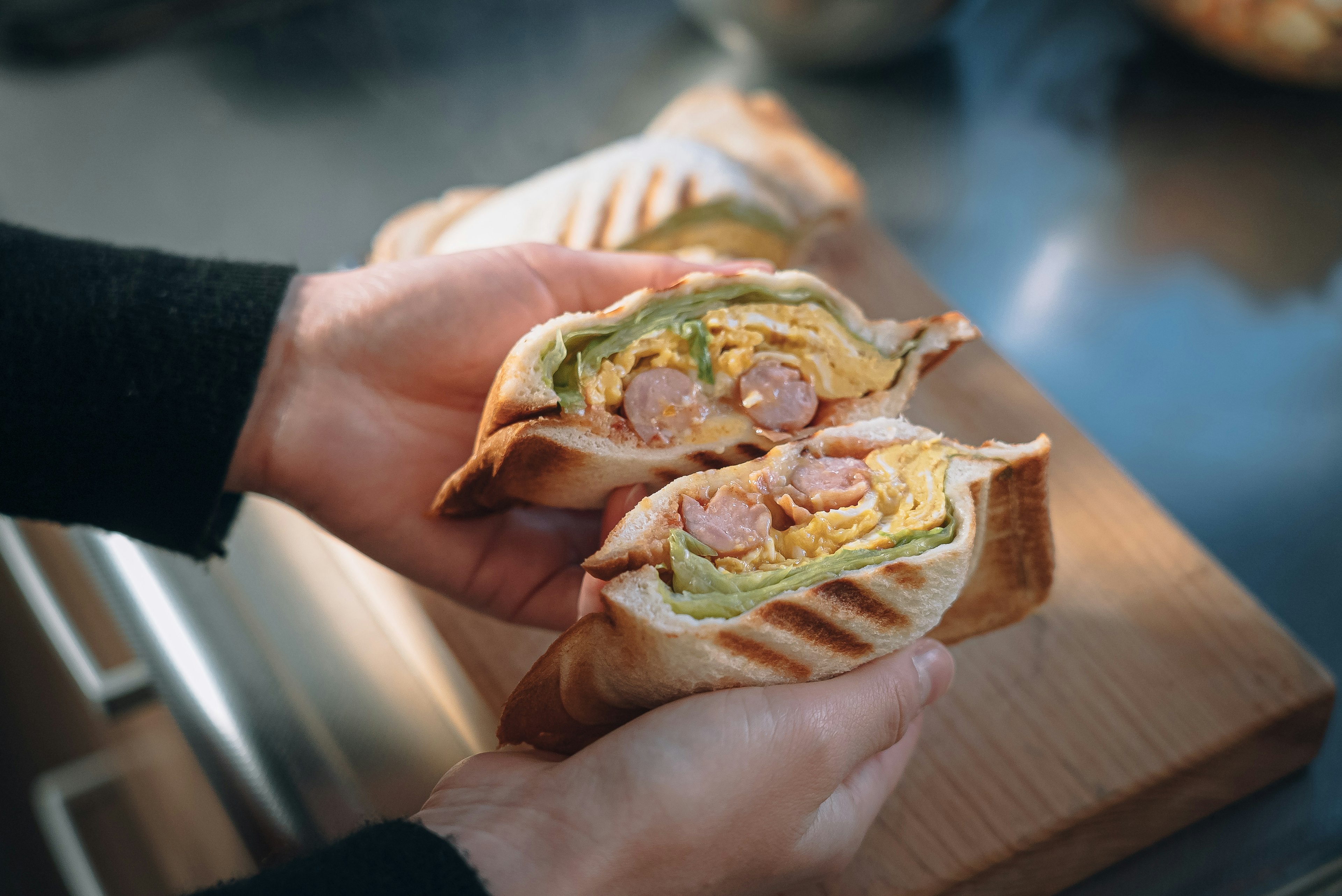 Cross-section of a hot sandwich held in hands with visible ingredients