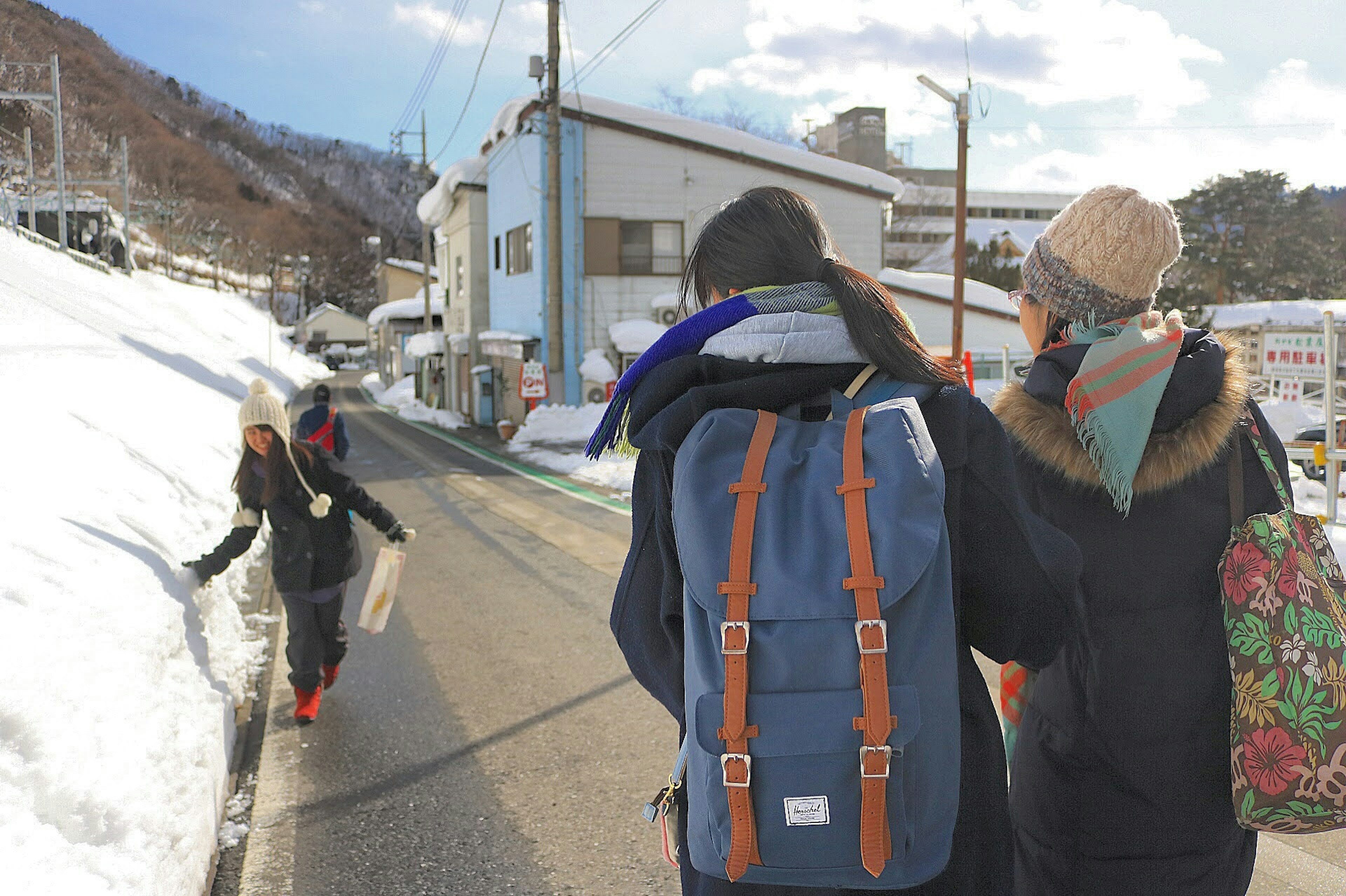 Personas caminando por una carretera nevada con viajeros que llevan mochilas