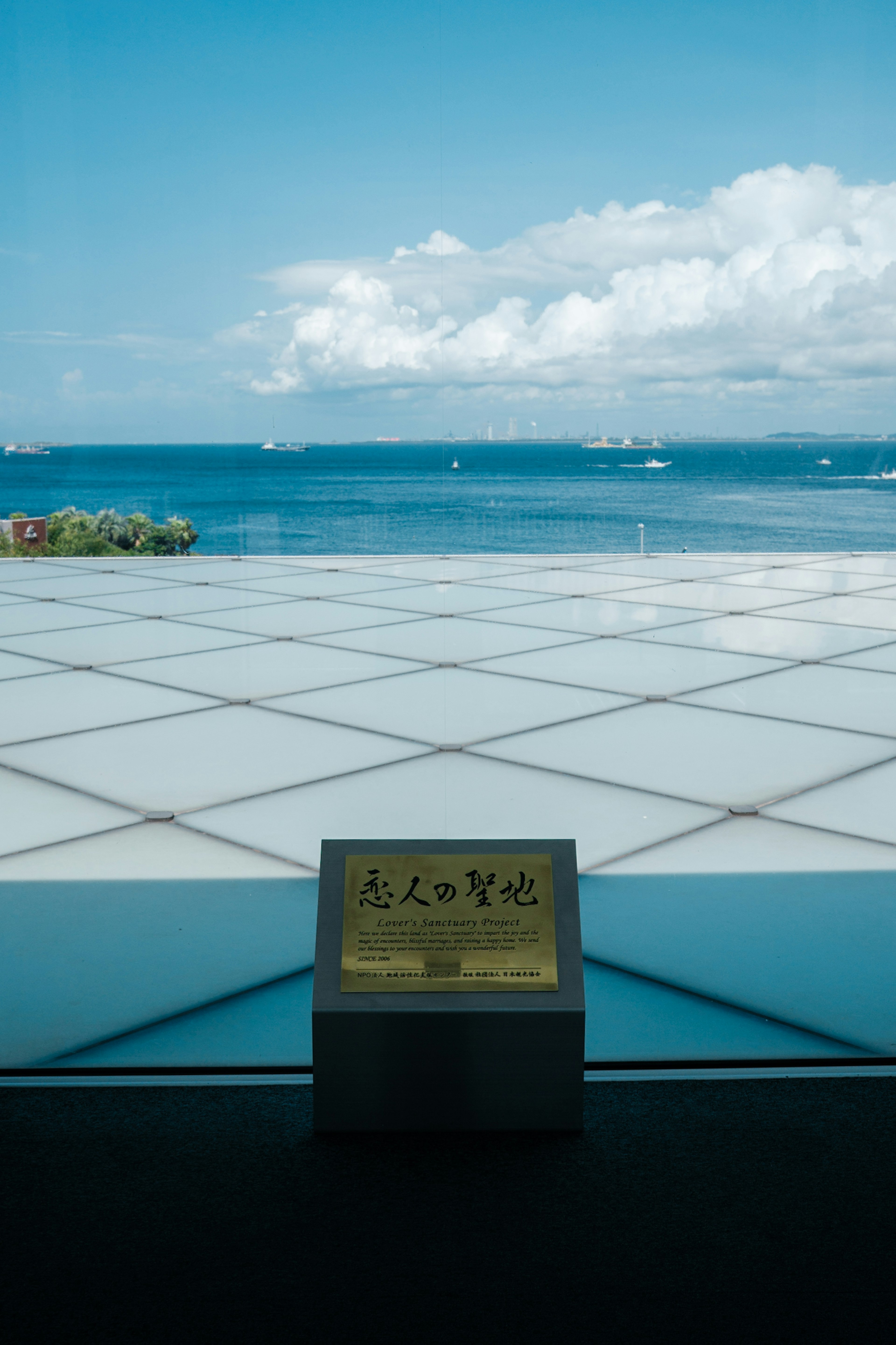 A square table with a golden plate against a backdrop of blue sea and white clouds