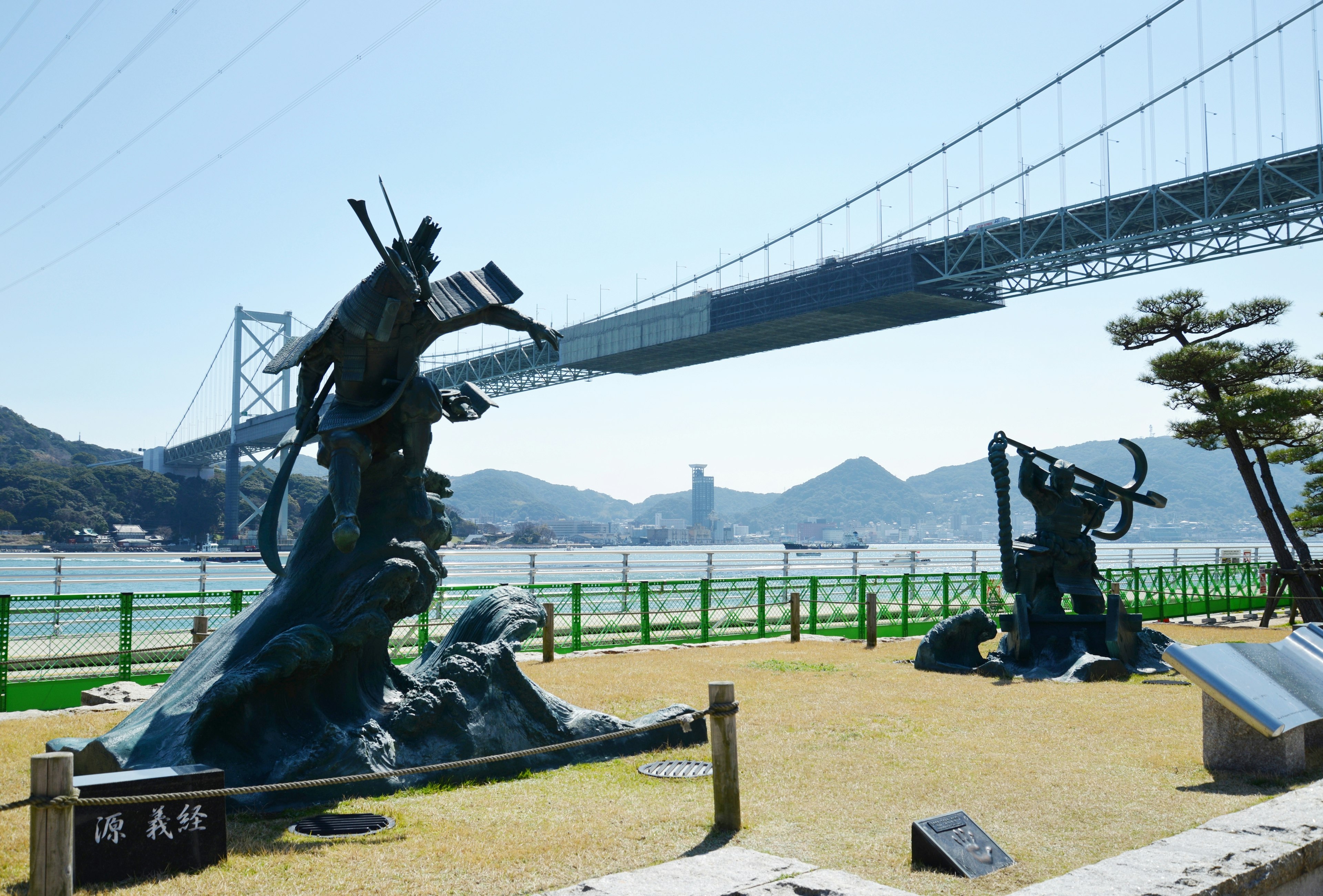 彫刻と橋が見える風景 公園にある青銅の彫刻と海の背景