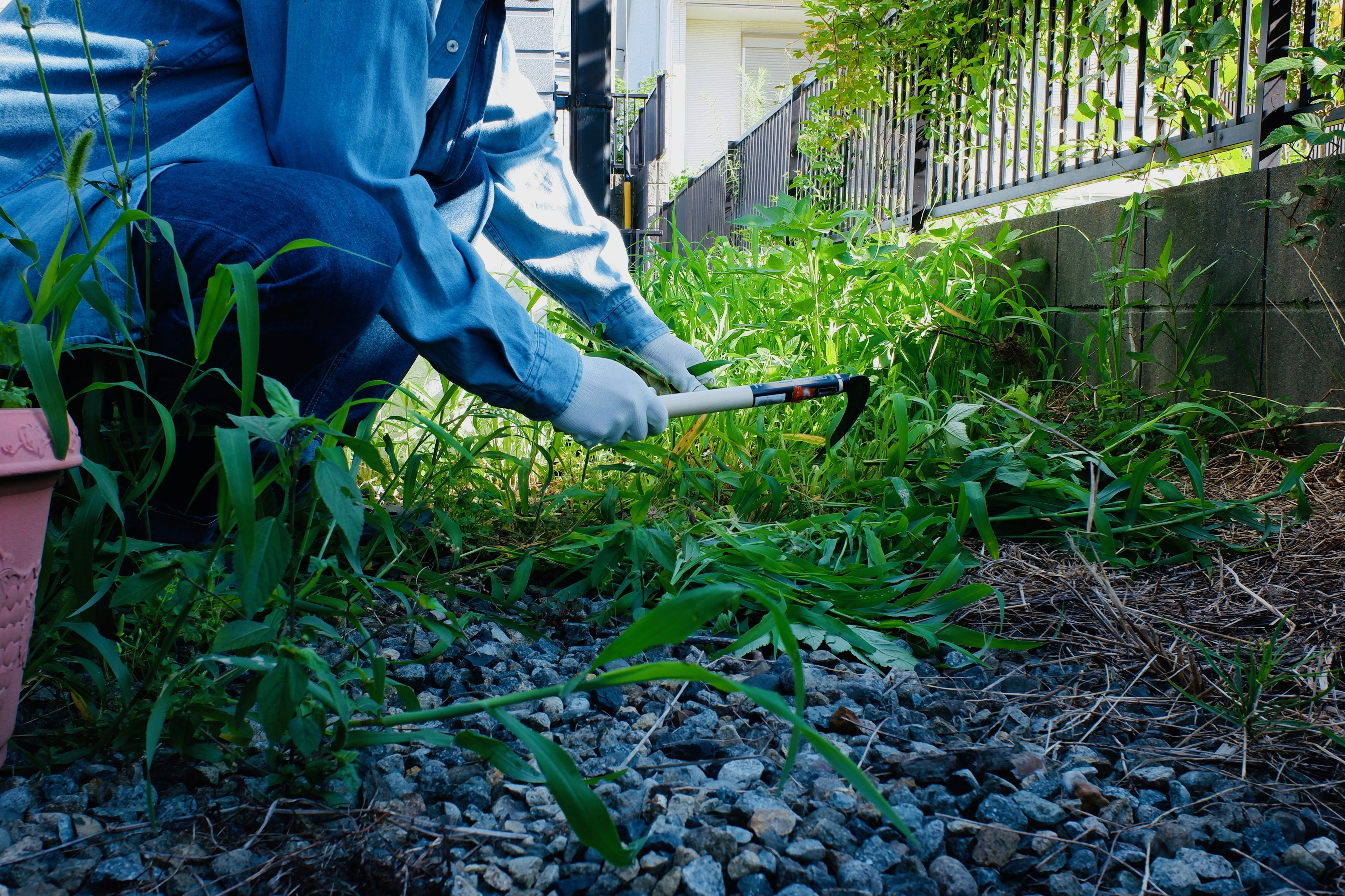 Person weeding a garden area with tools