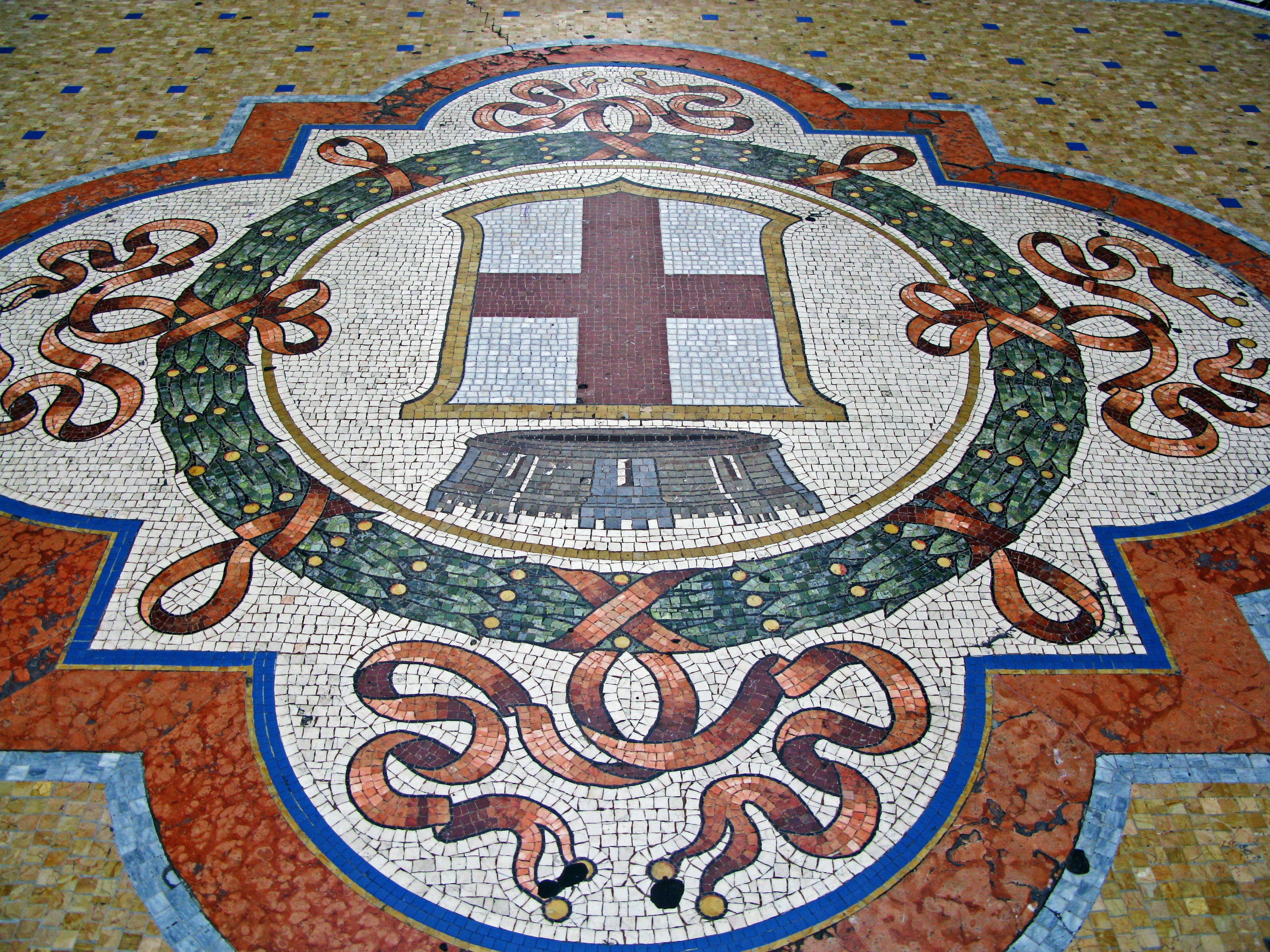 Mosaic floor featuring a coat of arms with a cross and floral wreath