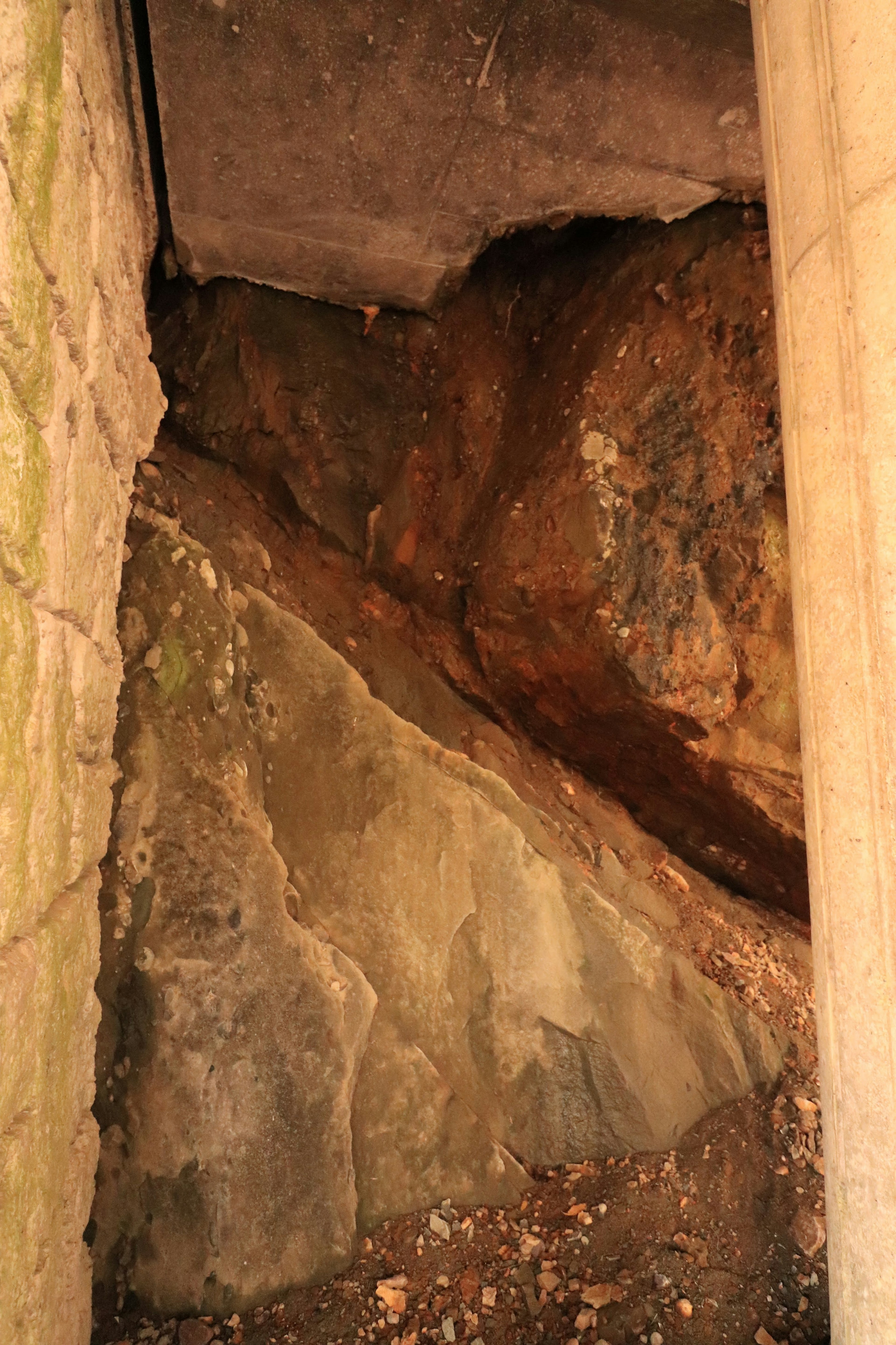 Interior view featuring rocks and a column in a dimly lit space