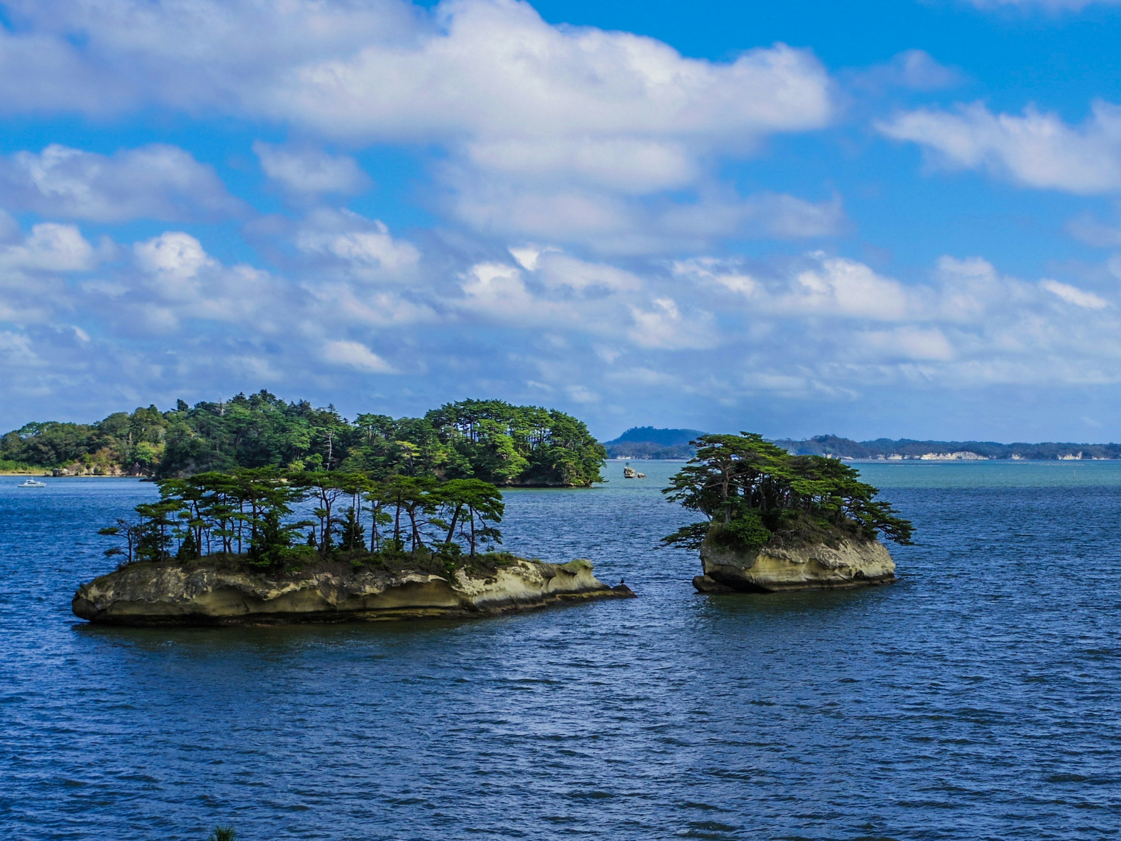 Pemandangan indah pulau kecil dengan vegetasi subur dikelilingi oleh air dan langit biru