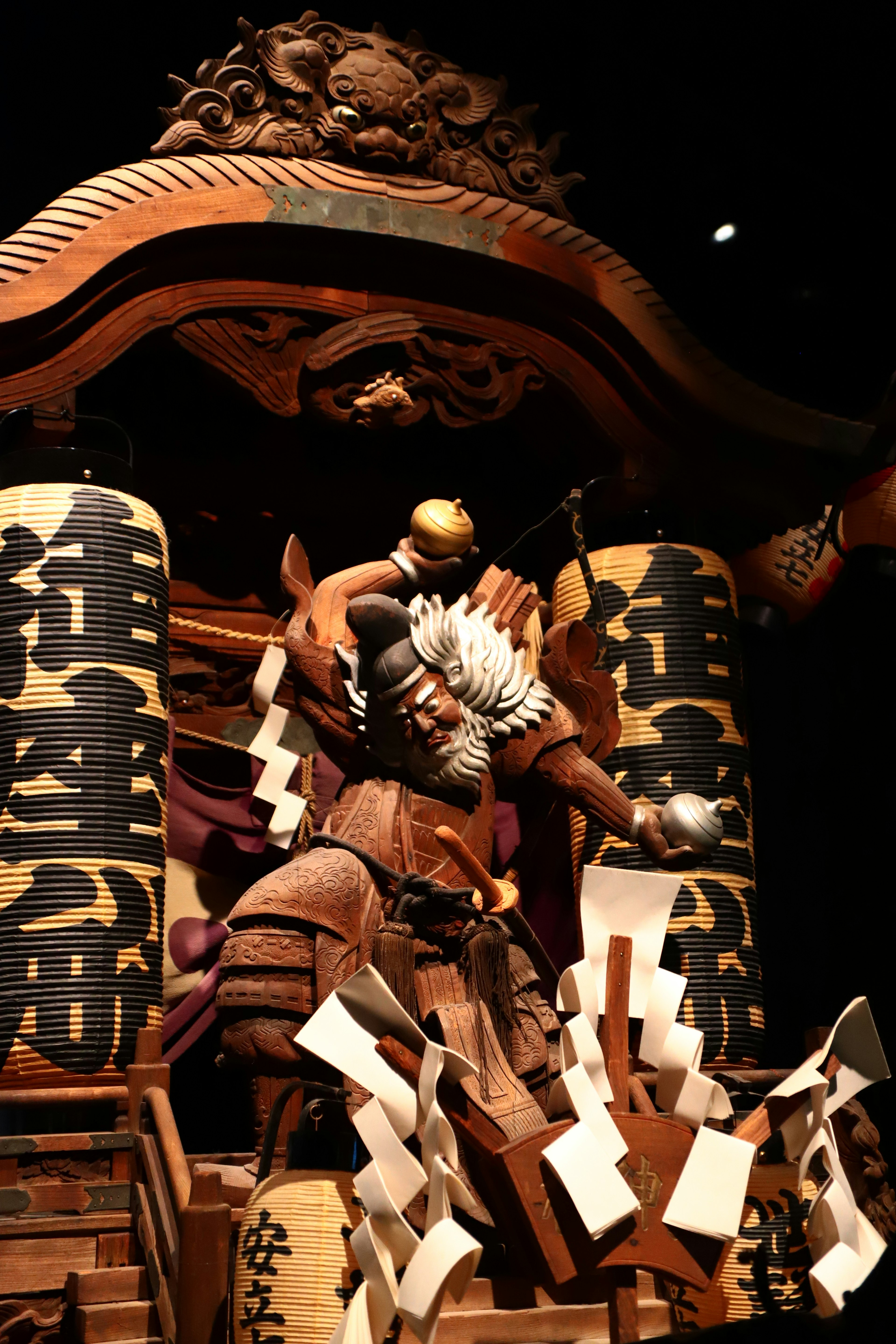 Sculpture de char élaborée pour un festival japonais traditionnel avec une grande figure de divinité et un arrière-plan décoratif