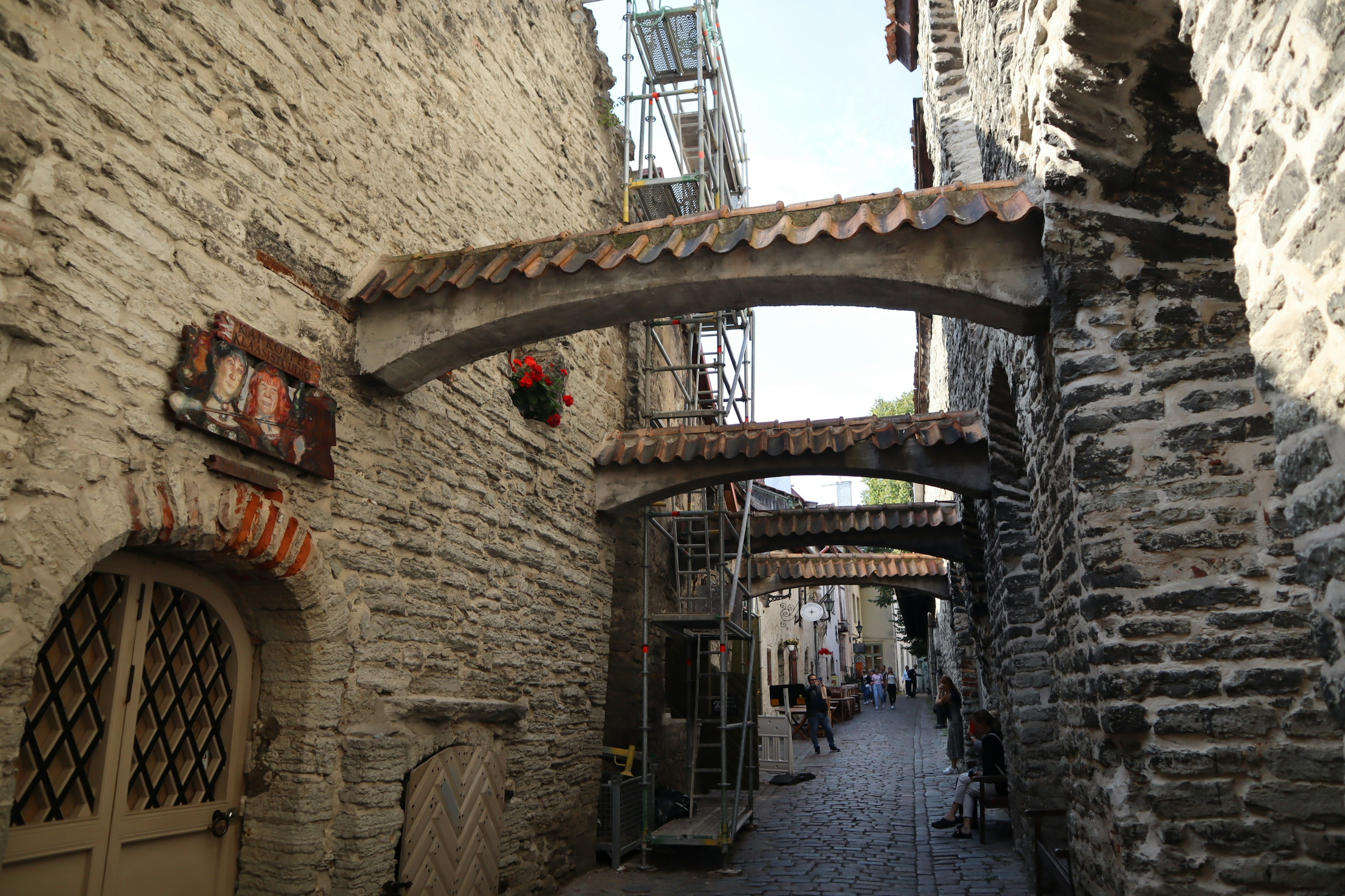 Narrow cobblestone street with stone walls and arched roofs