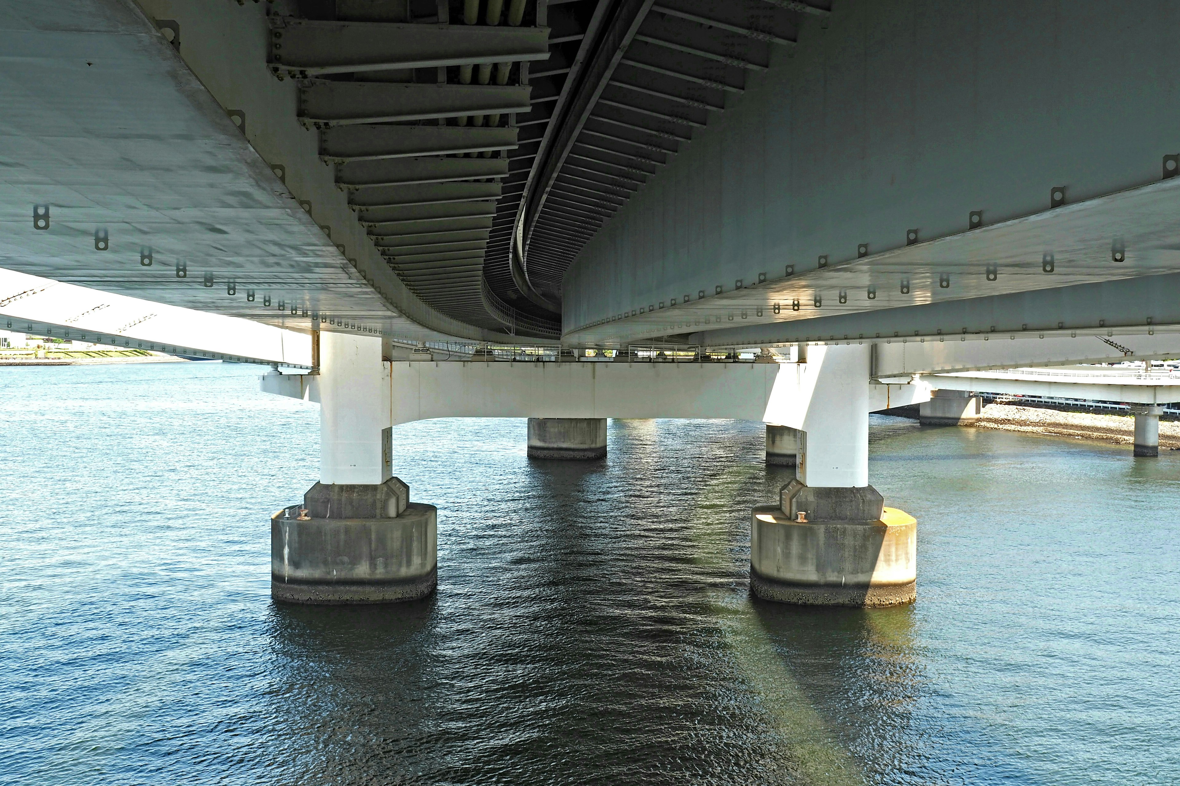 Vue depuis sous un pont montrant des colonnes et des reflets sur l'eau