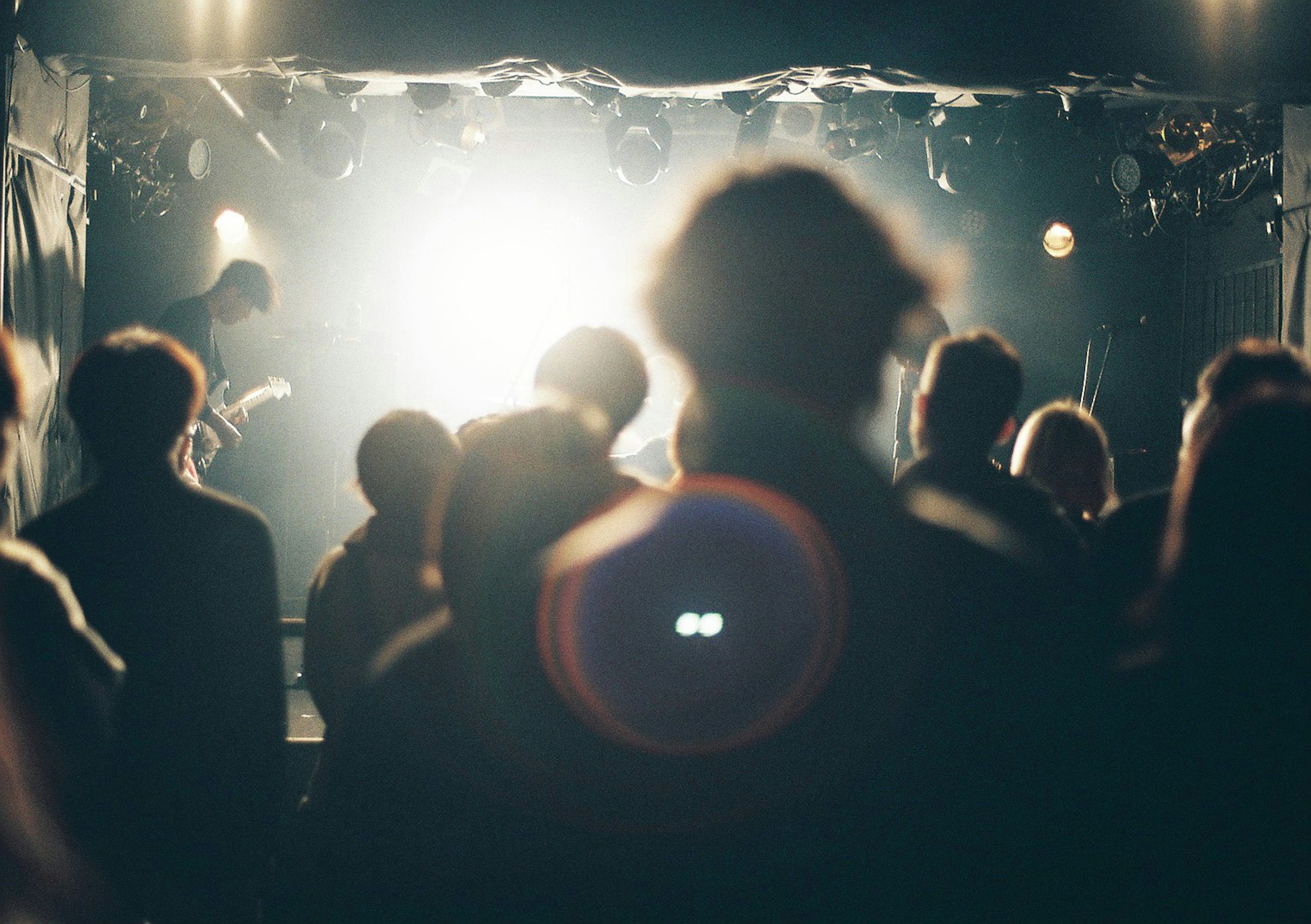 Silhouette of an audience enjoying a live performance with bright stage lights