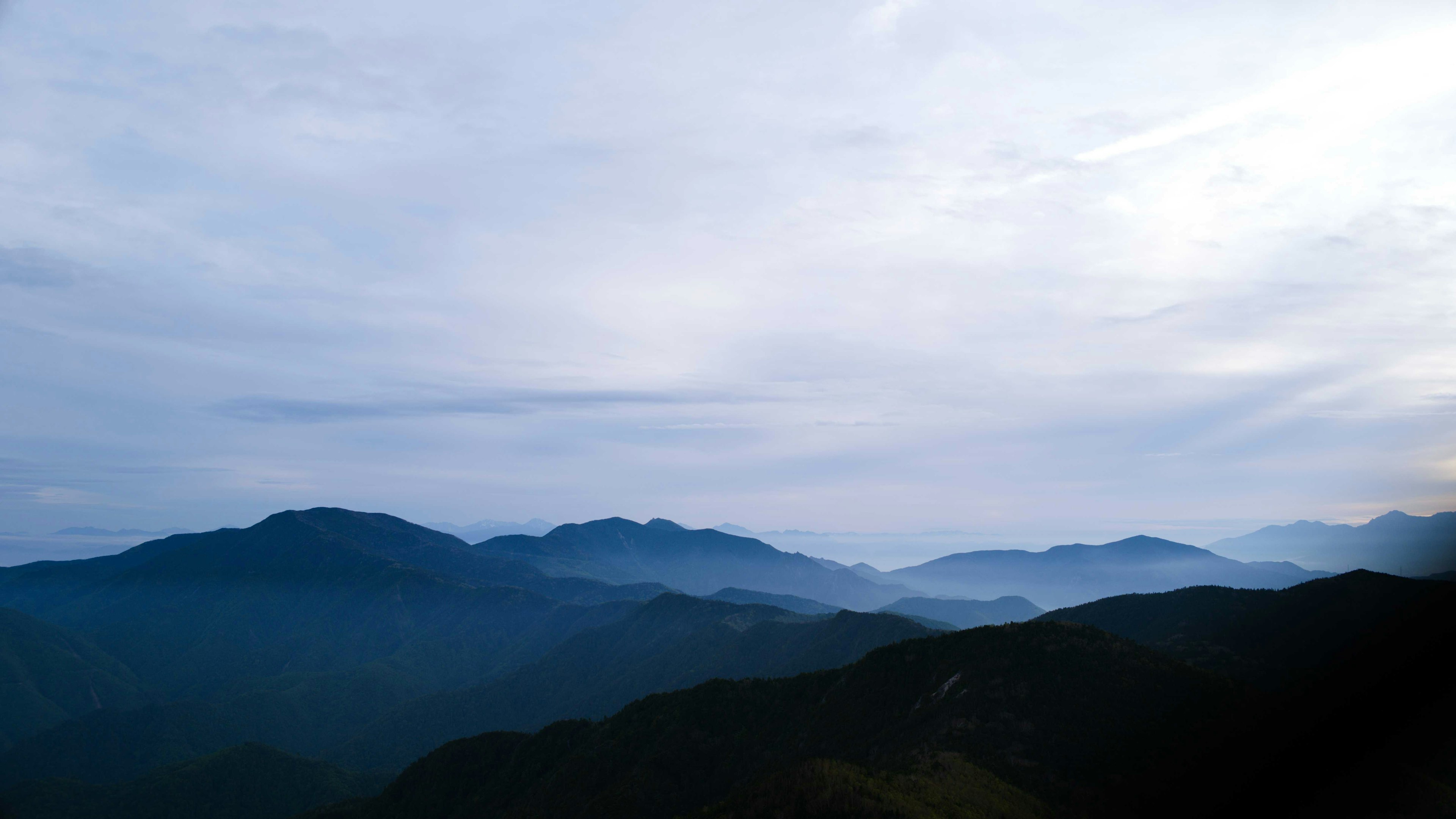 藍色山脈籠罩在霧中，天空多雲