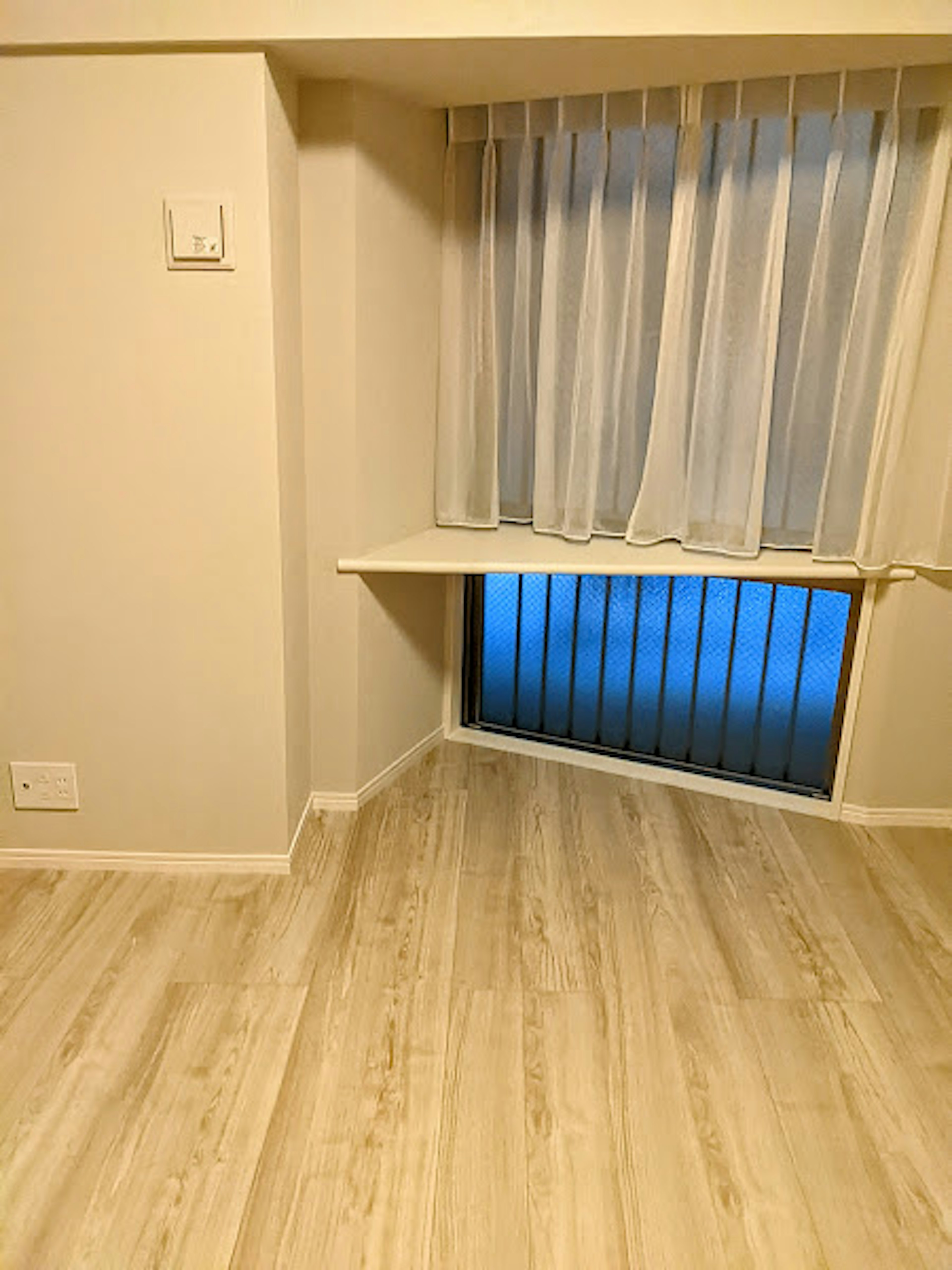 Esquina brillante de una habitación con suelo claro cortinas blancas transparentes y una ventana que muestra luz azul