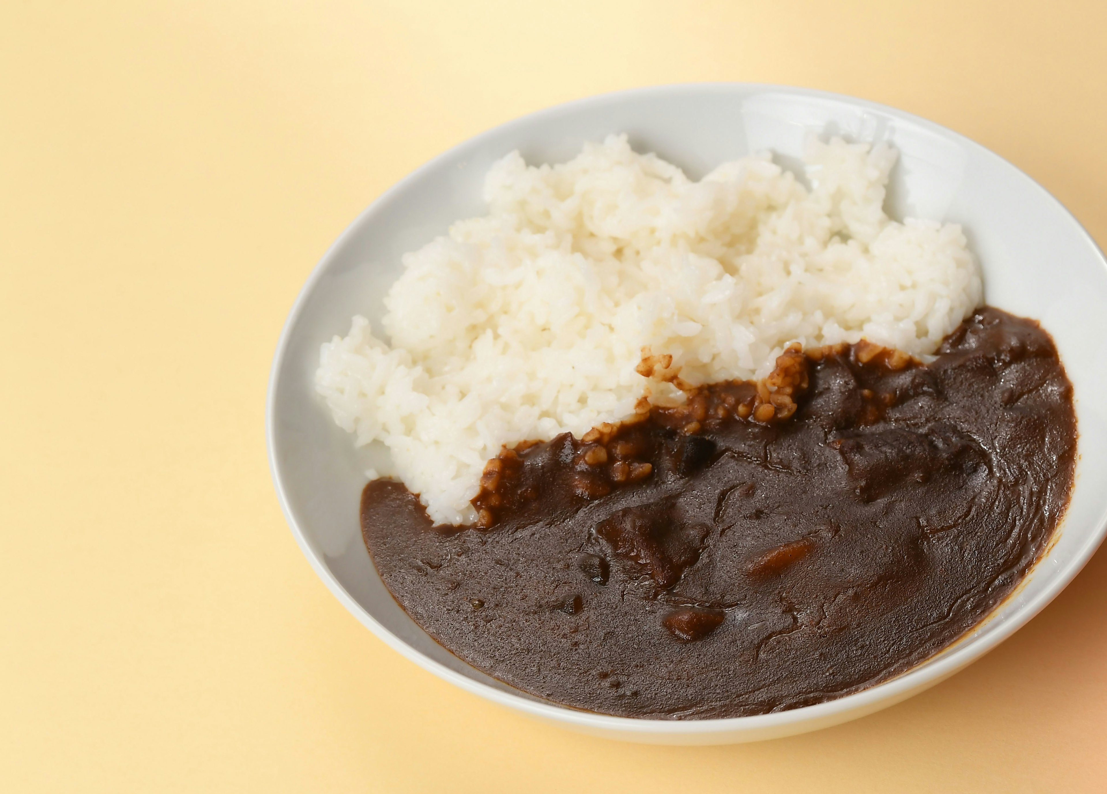 Mangkuk nasi dengan kari di latar belakang kuning