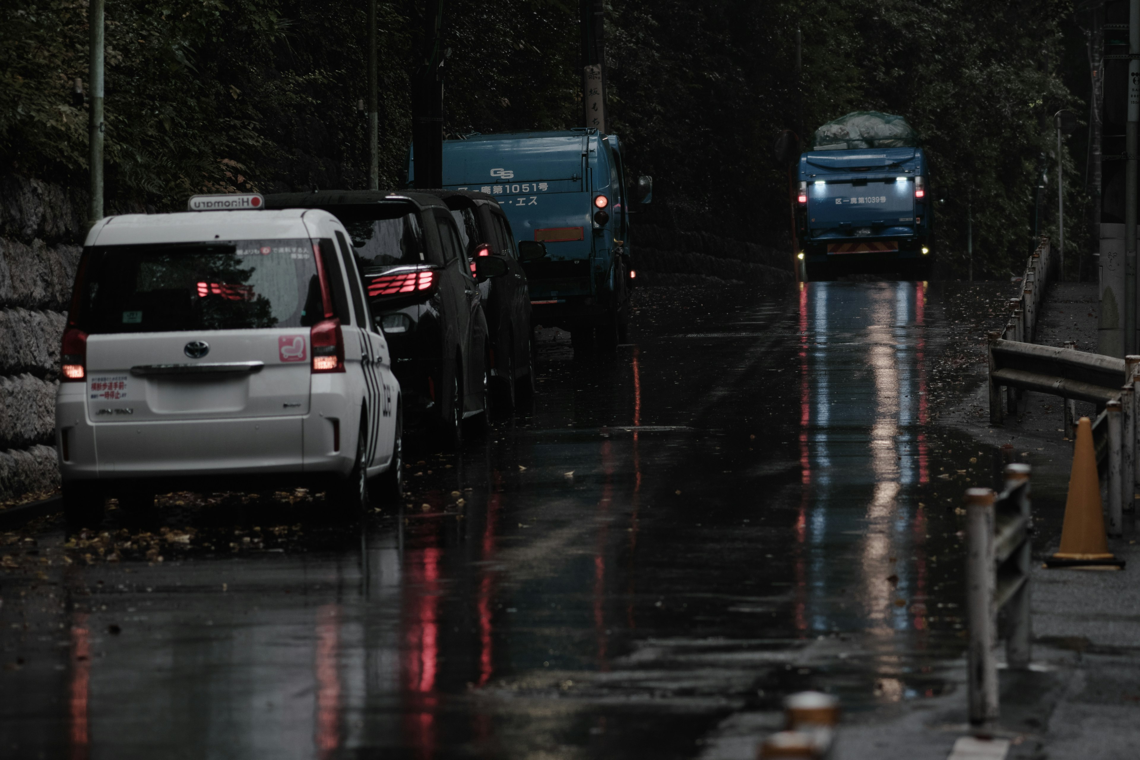 Coches estacionados en una calle lluviosa con reflejos