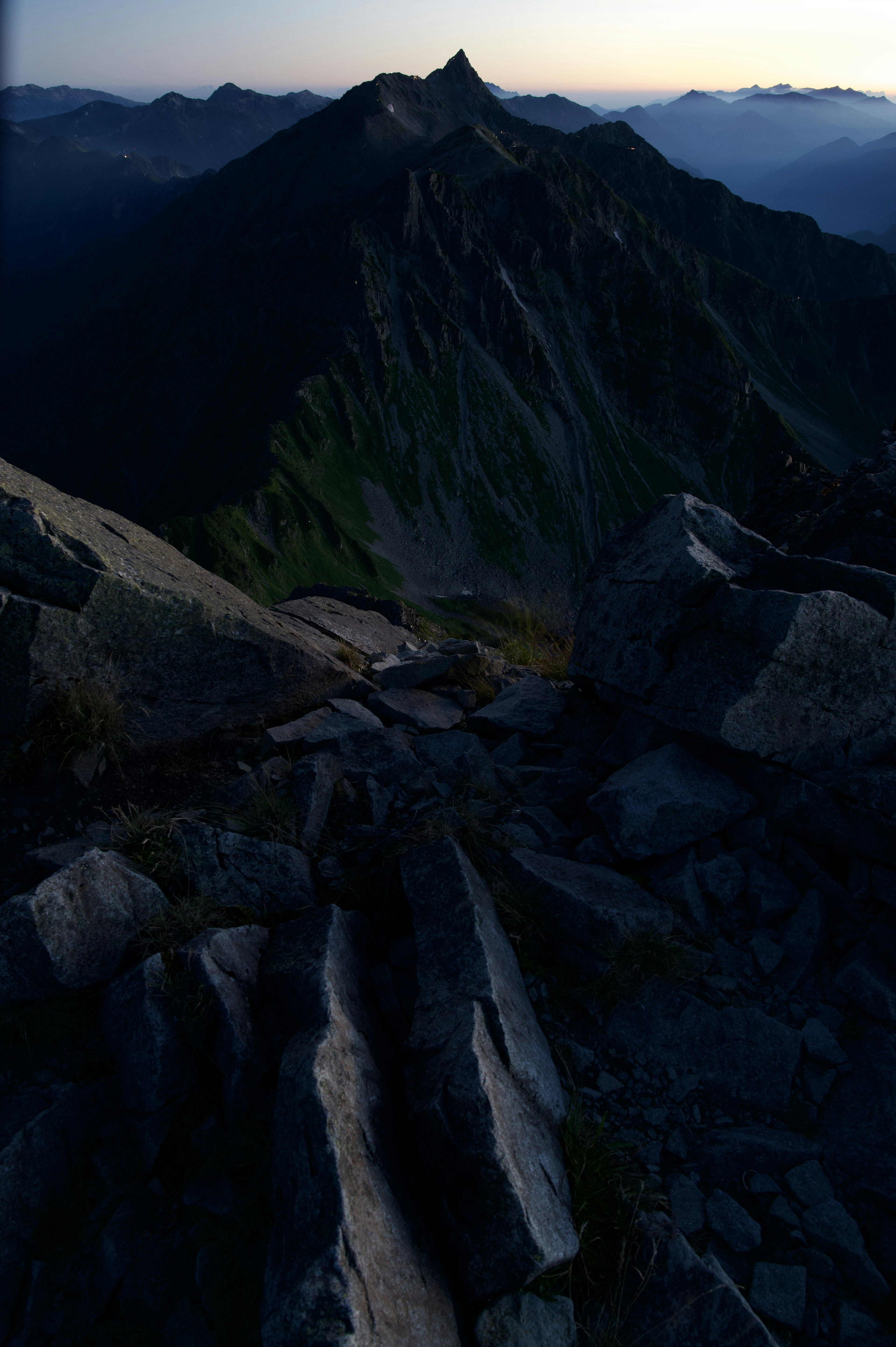 Vue du sommet d'une montagne avec un terrain rocheux et des sommets lointains