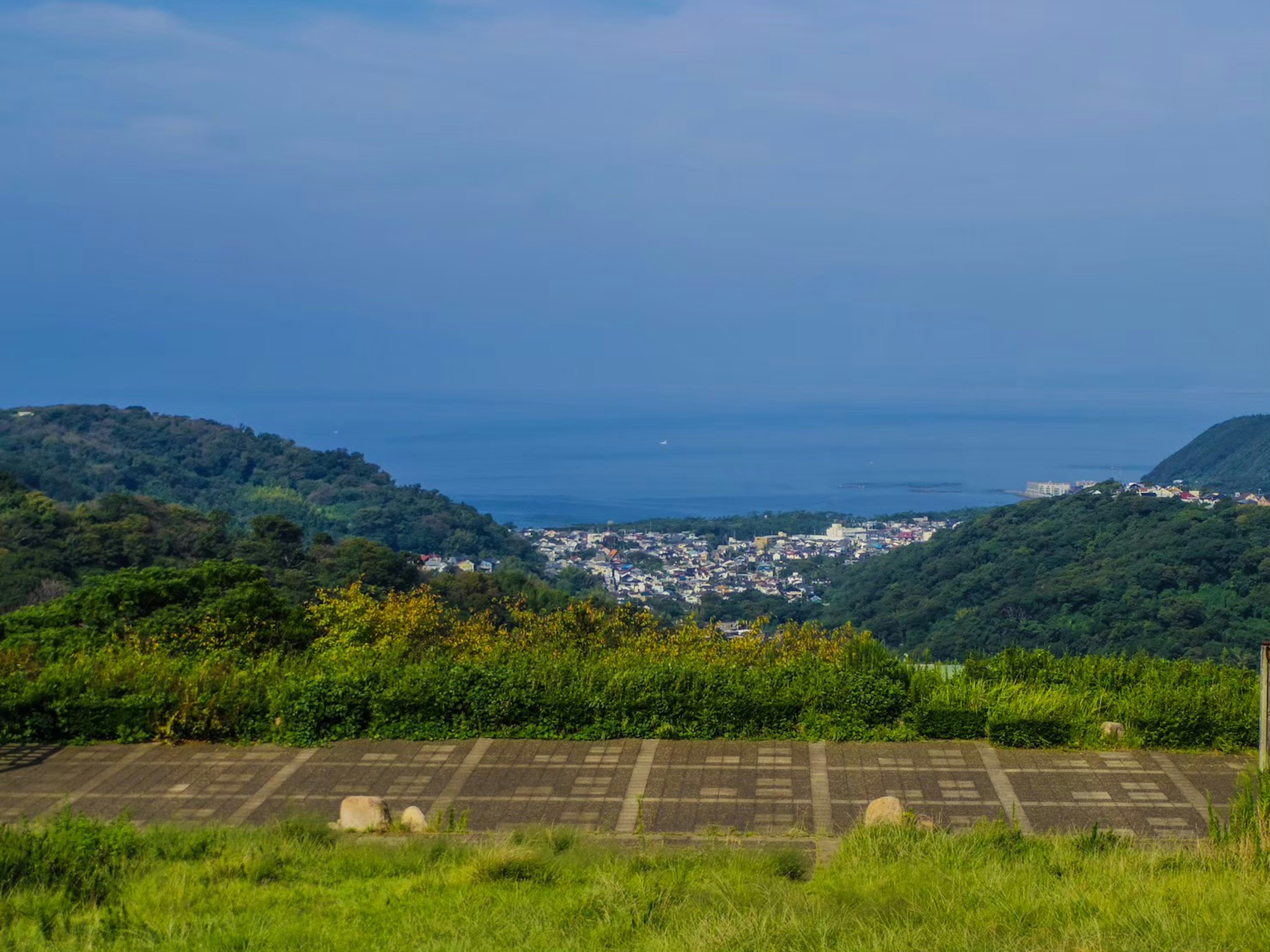 Vue panoramique avec mer bleue et collines vertes en arrière-plan