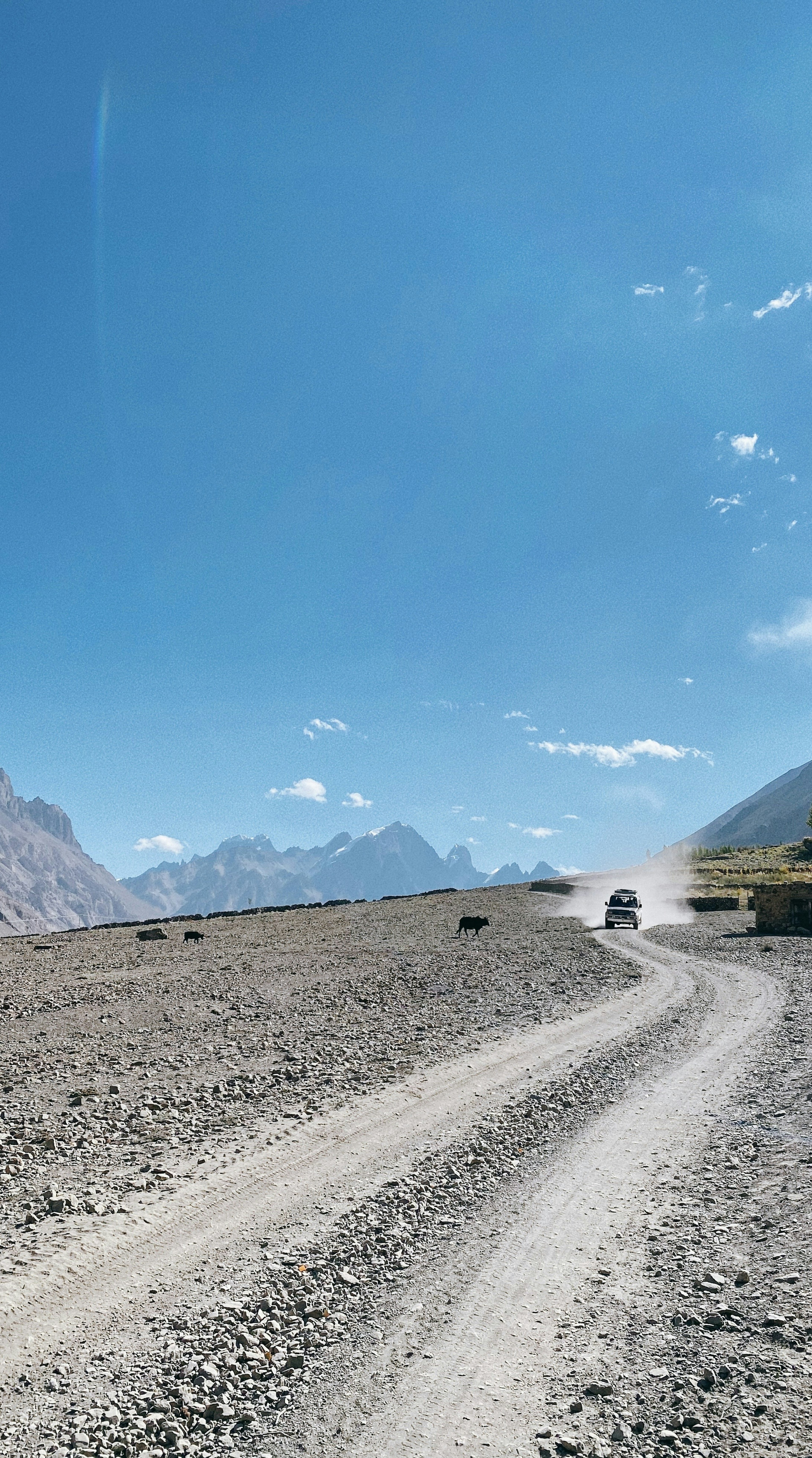 Strada di ghiaia che porta verso le montagne sotto un cielo blu chiaro