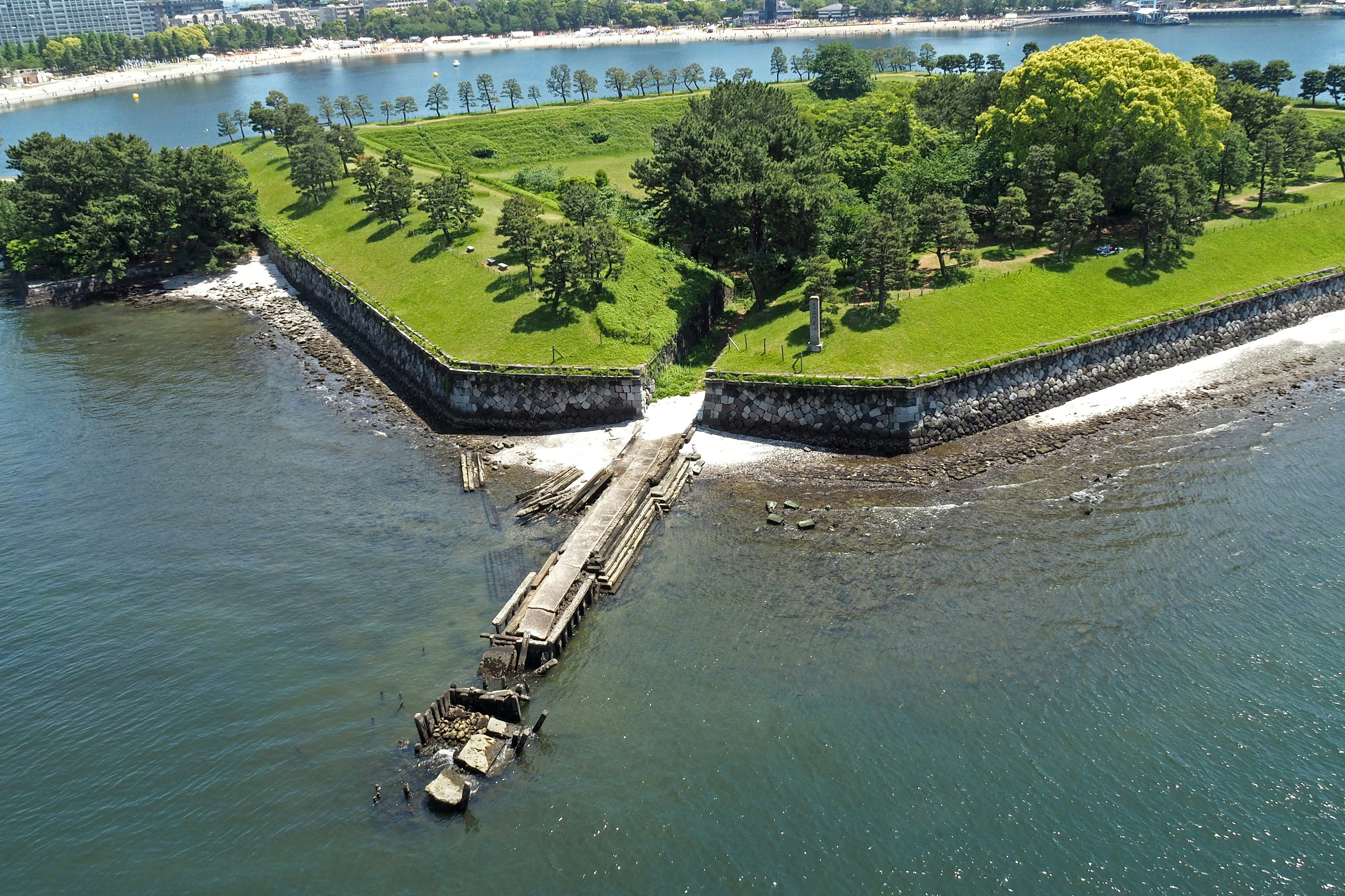 Aerial view of a green island surrounded by trees a bridge extending into the water