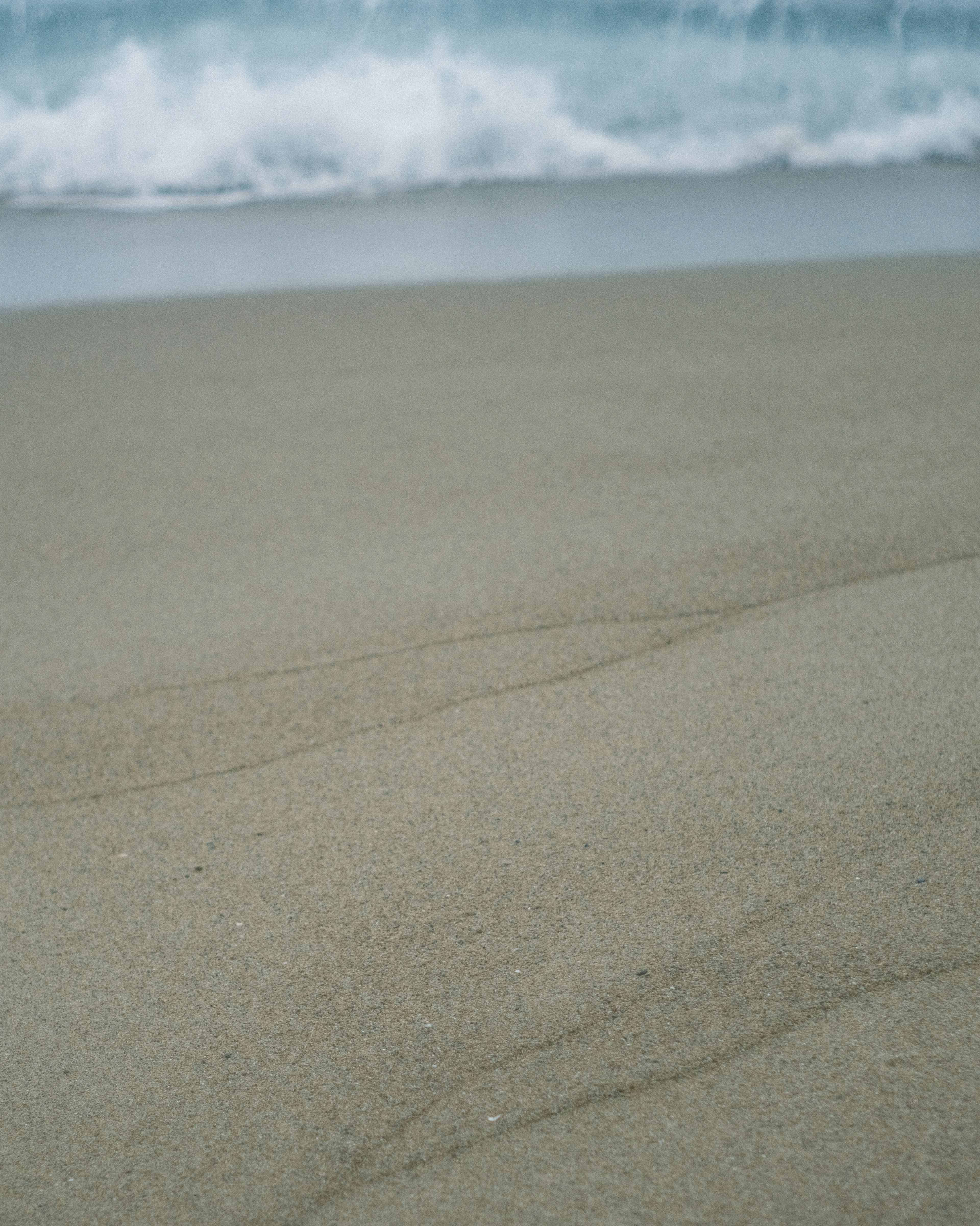 Courbes douces et texture d'une plage de sable avec des vagues qui approchent