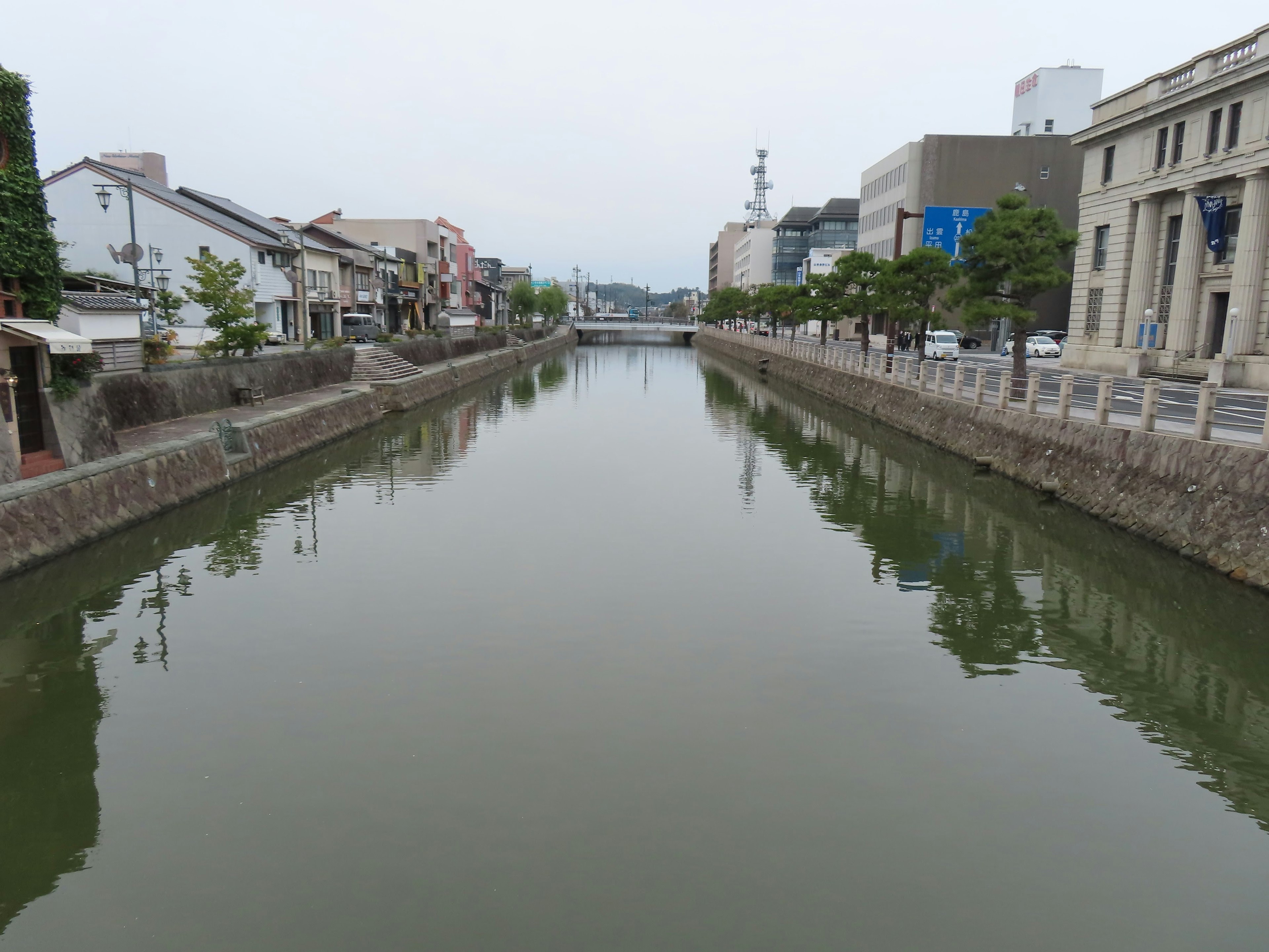 静かな川の風景と周囲の建物が映る