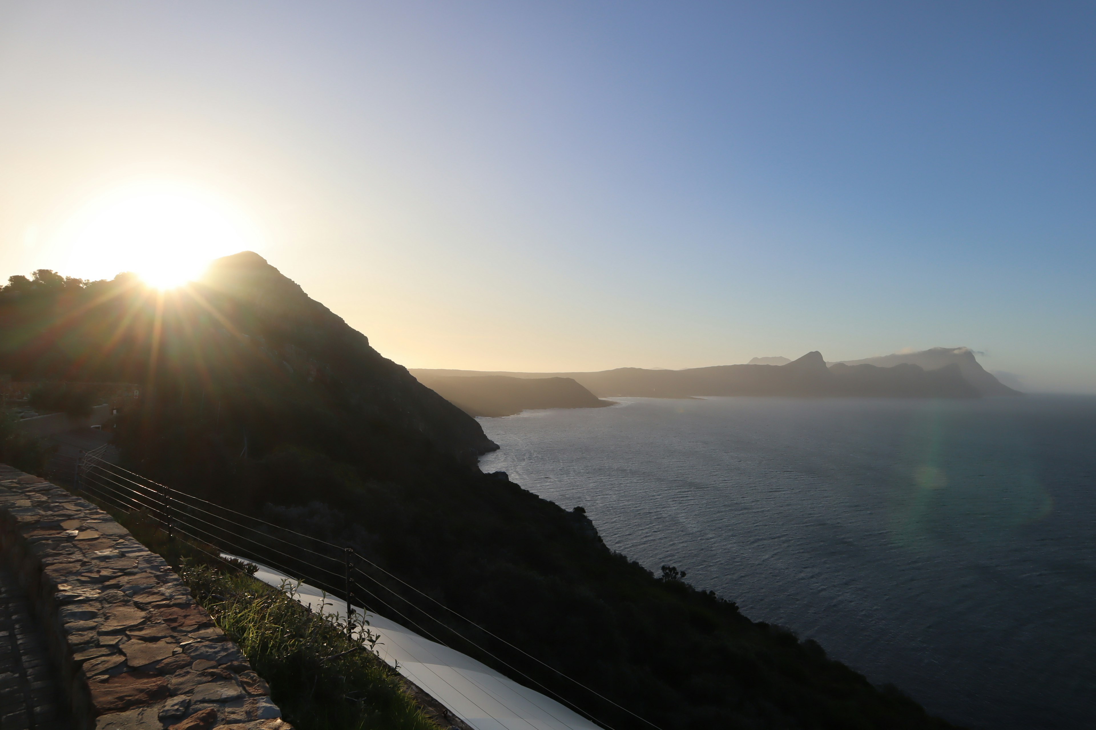 Vista costiera panoramica con montagne e tramonto sull'oceano