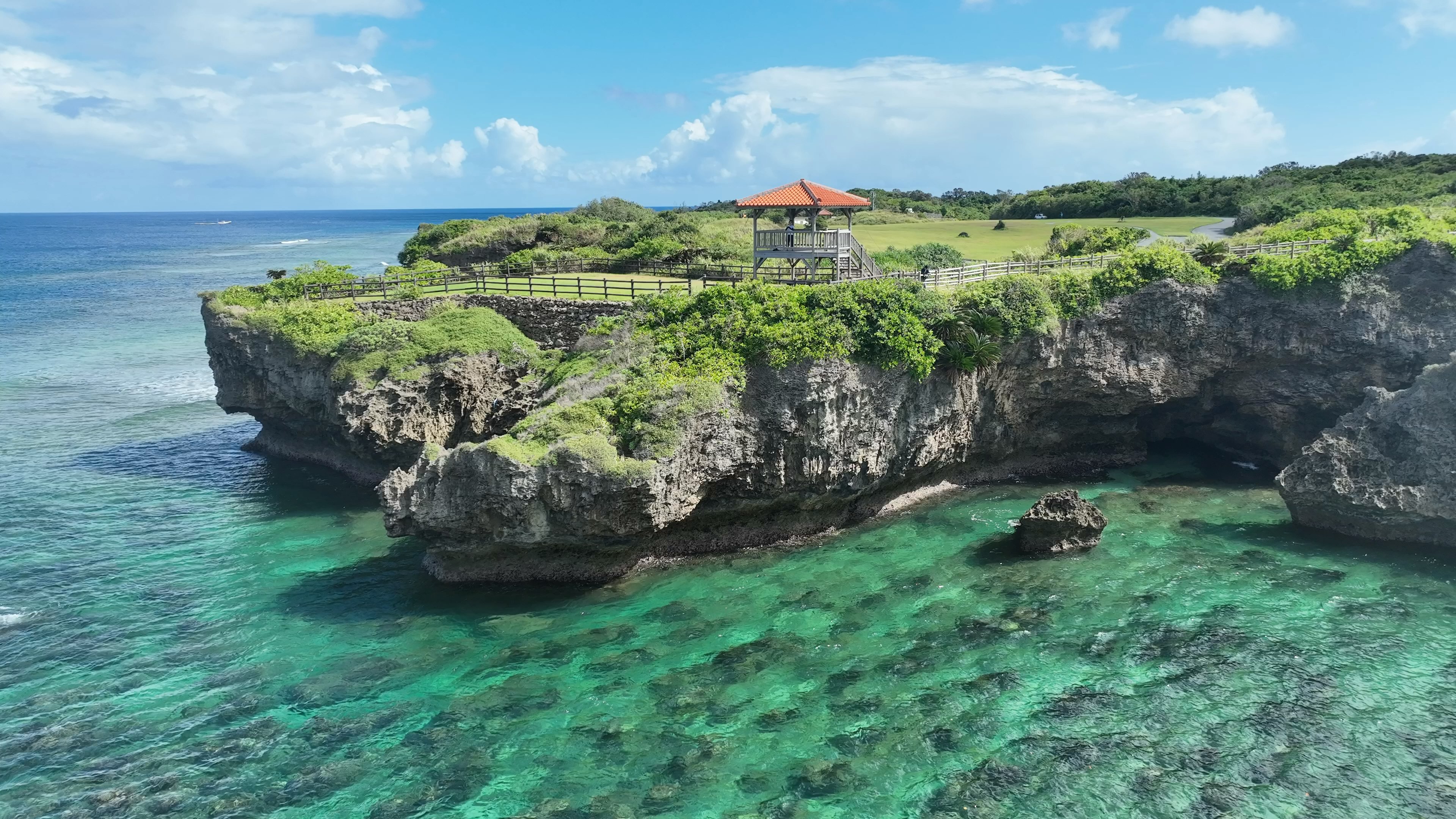 Pemandangan pantai yang indah dengan tebing hijau dan air biru jernih