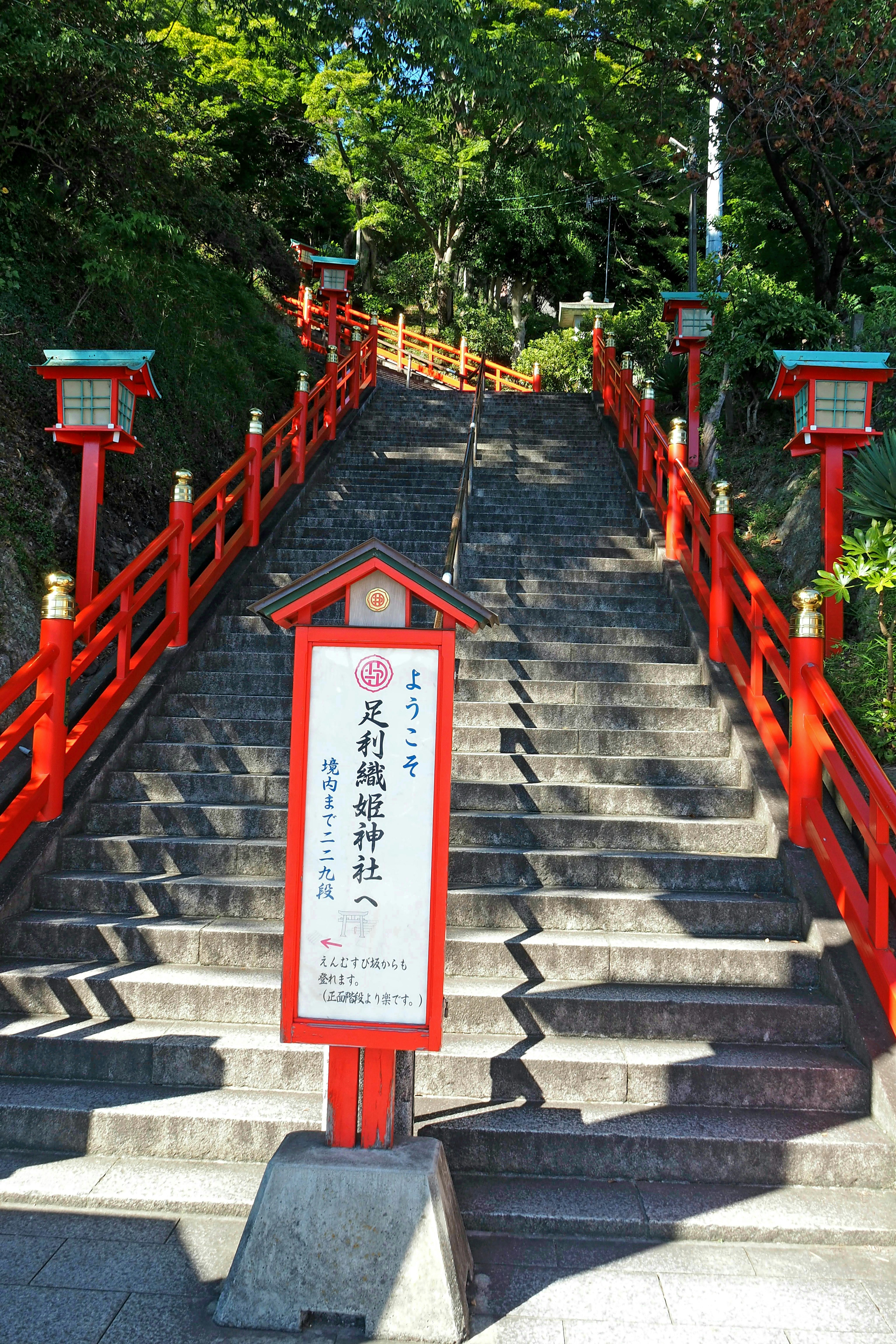 赤い手すりの階段と標識がある神社への道