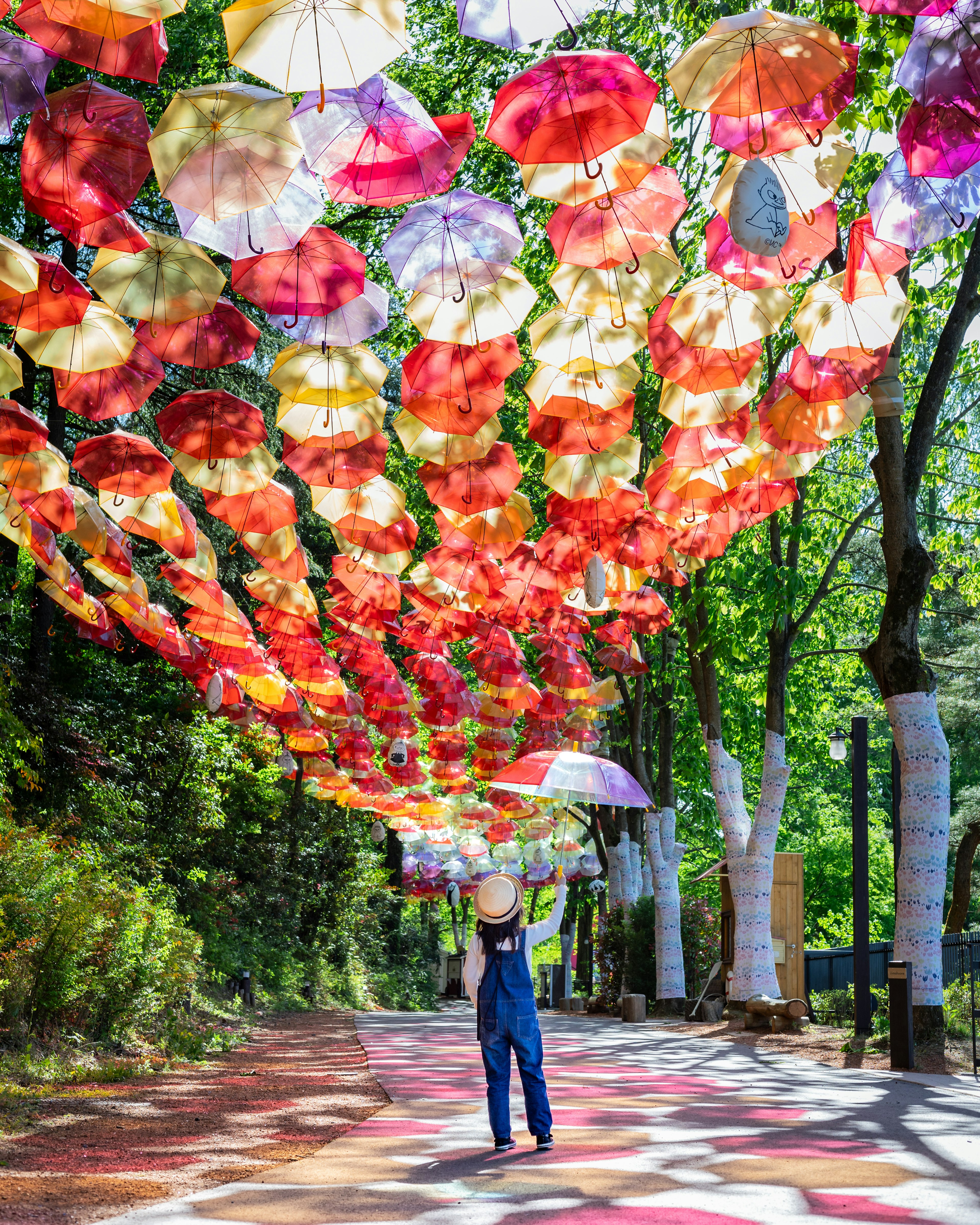 Child walking under colorful umbrellas on a green path