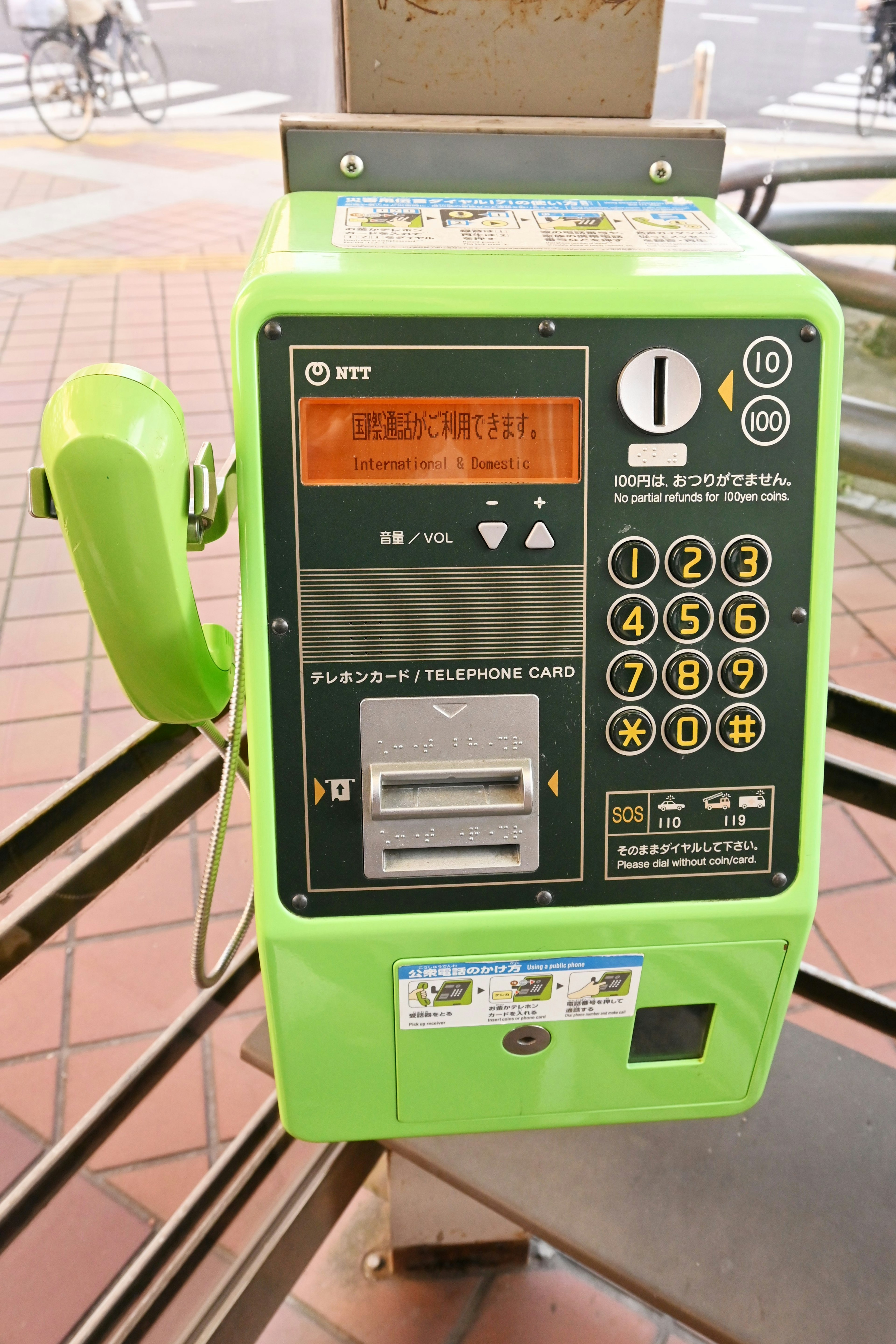 Image of a green public telephone with visible handset and number keypad