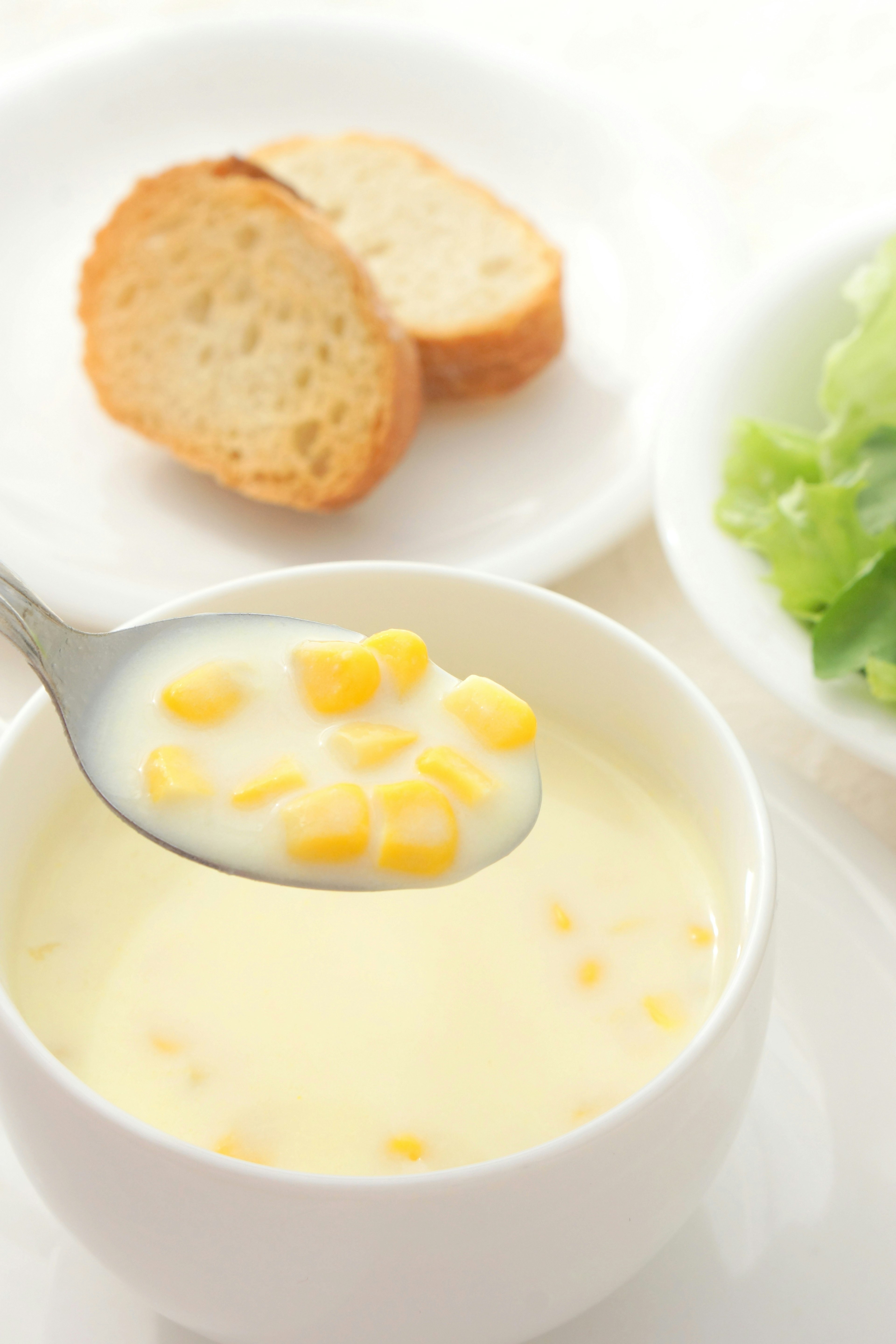 Soupe de maïs crémeuse avec du pain tranché et une salade à côté