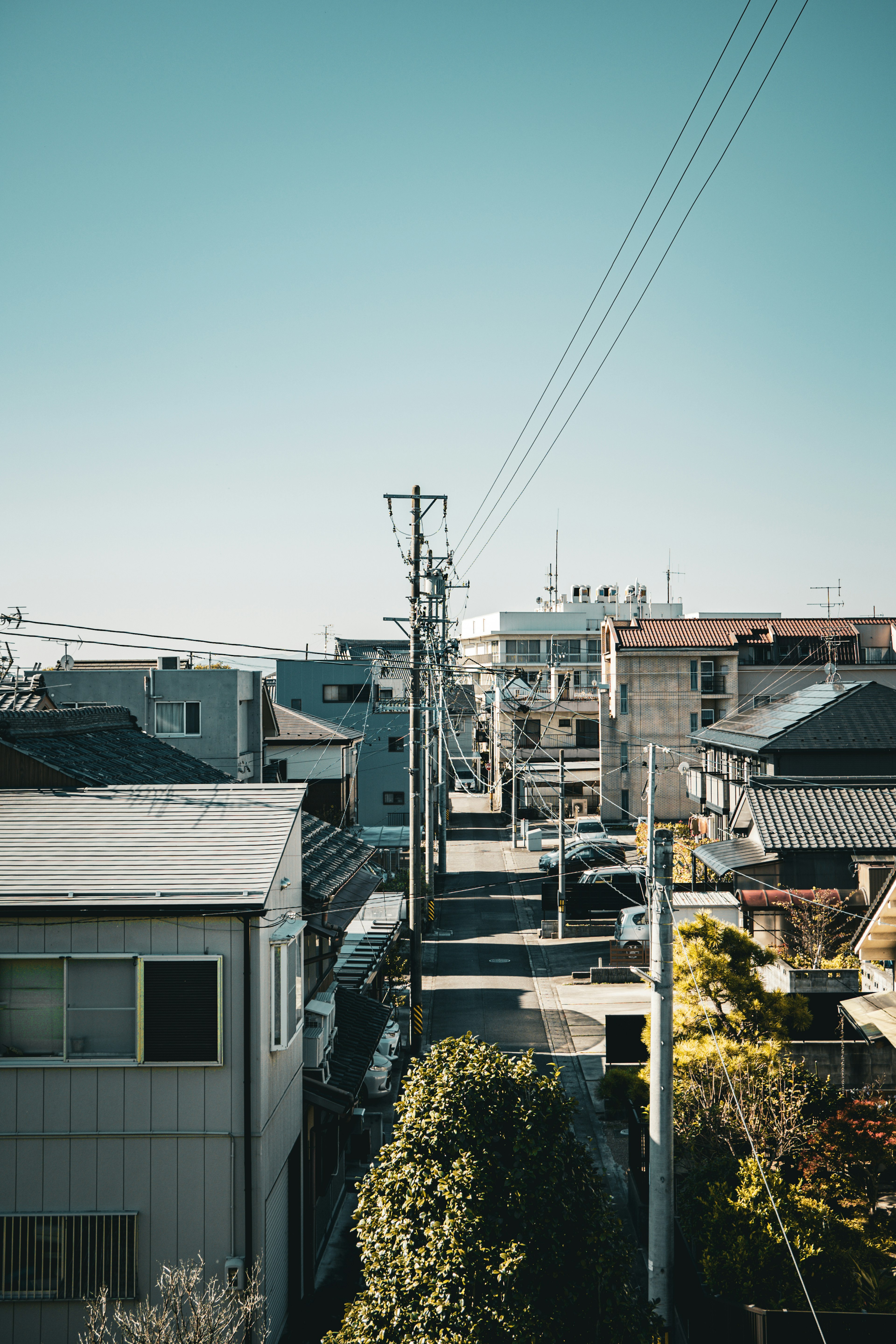 青空の下の住宅街の風景 電柱や電線のある狭い通りと家々