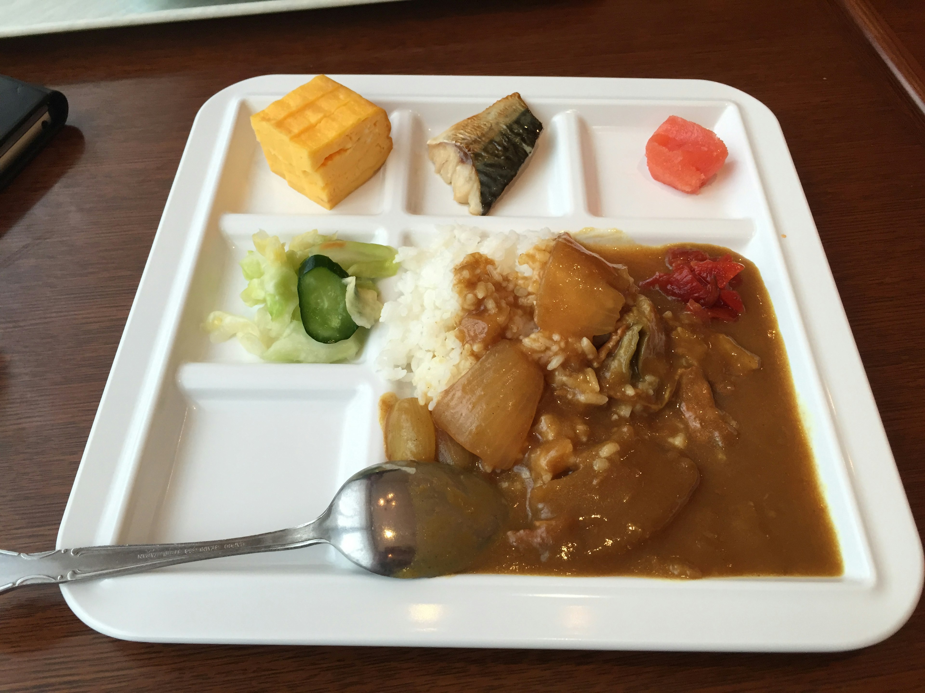 Curry rice served on a white plate with various side dishes