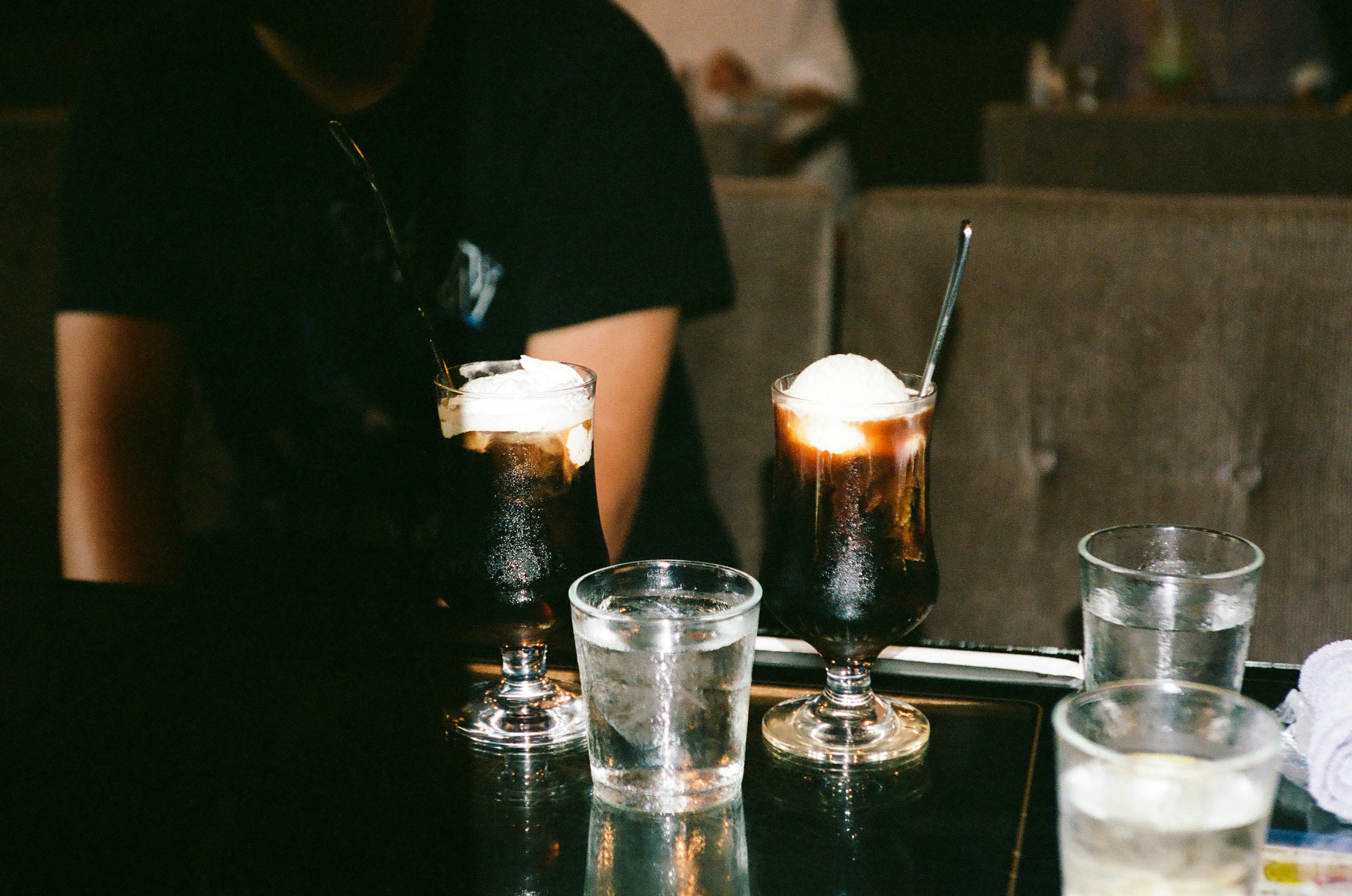 Dos vasos de café helado con helado y vasos de agua en una mesa