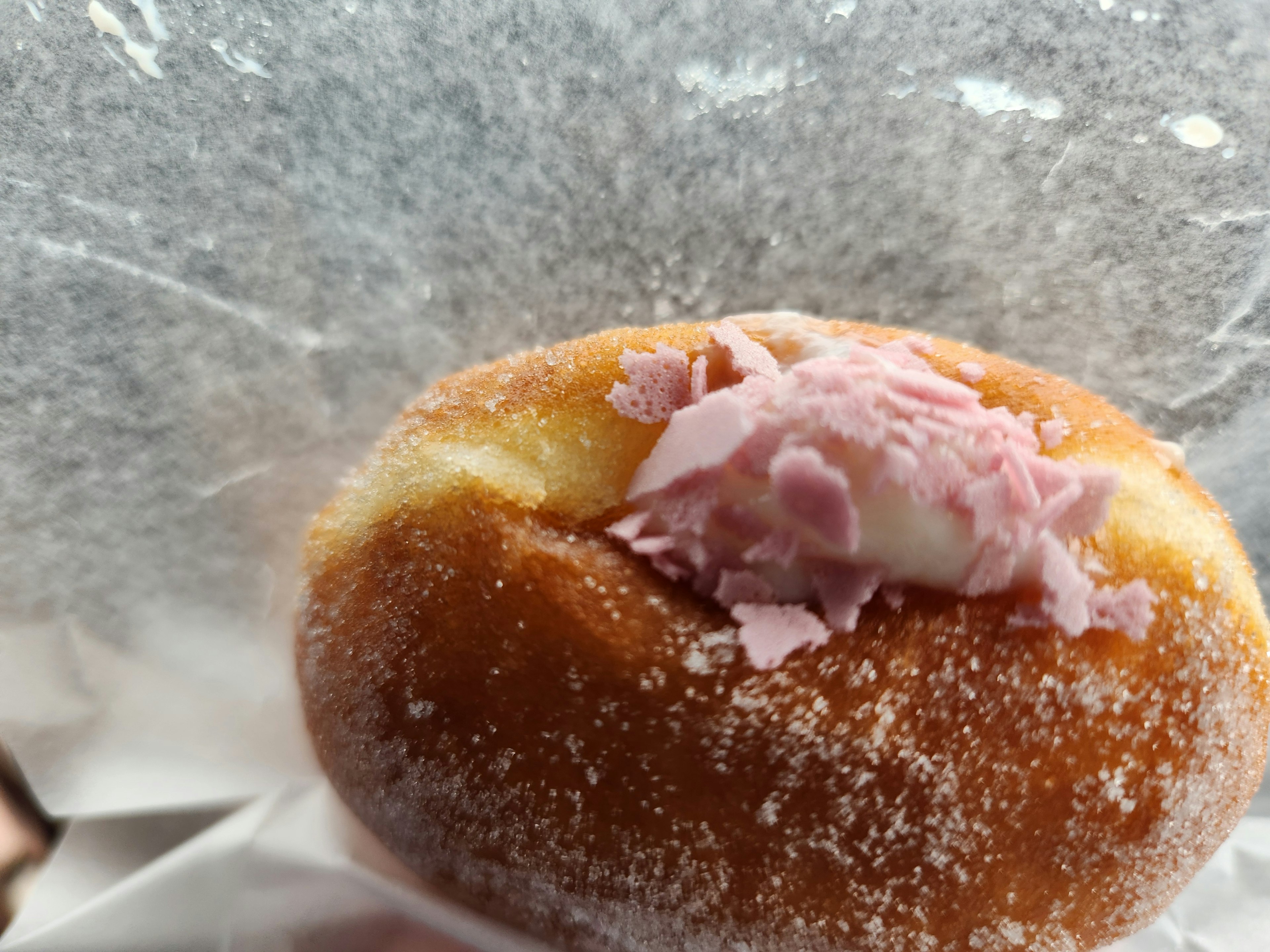 Sugar-coated donut topped with cream and pink filling