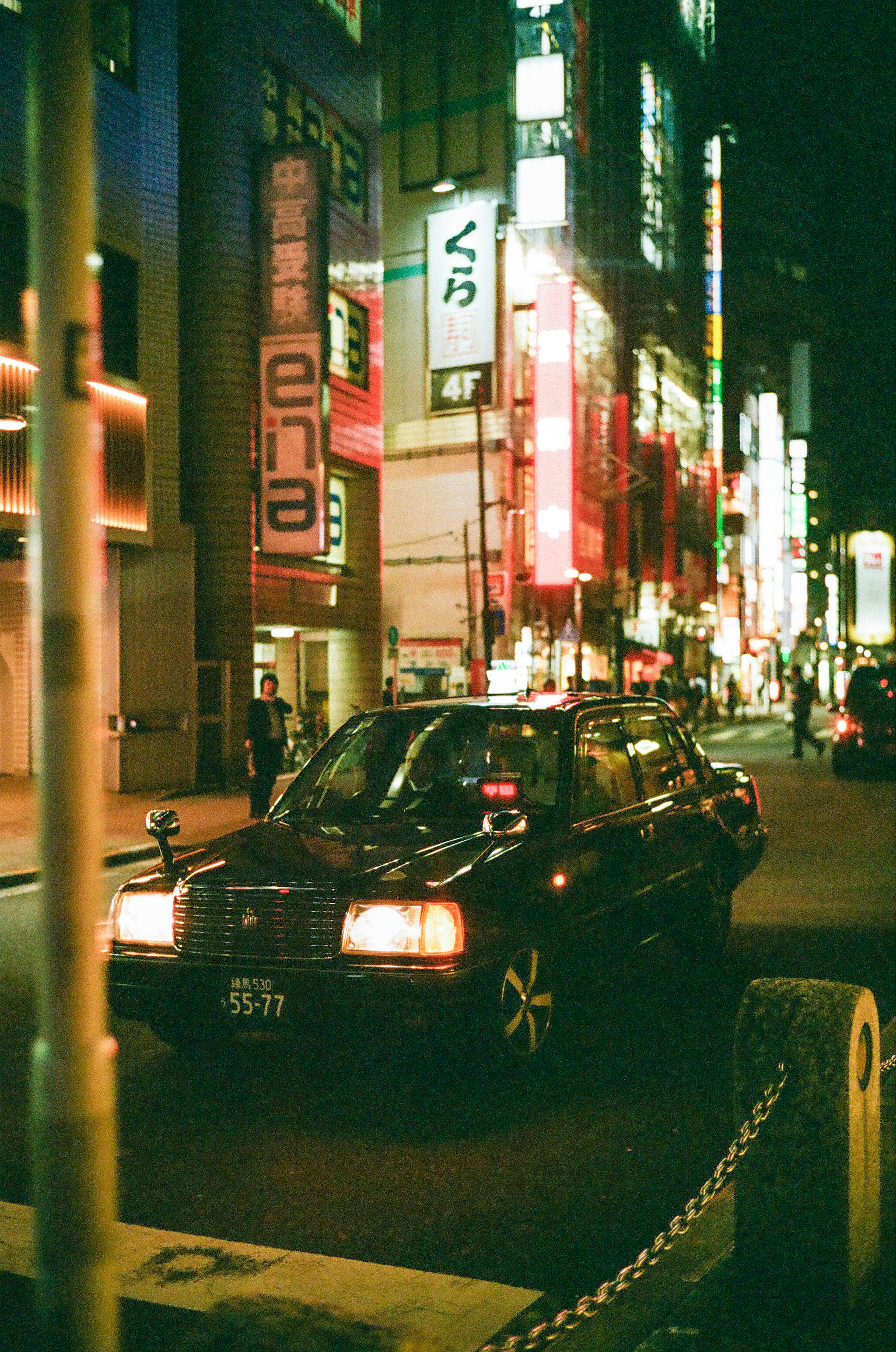 夜间在霓虹灯照亮的东京街道上行驶的黑色出租车