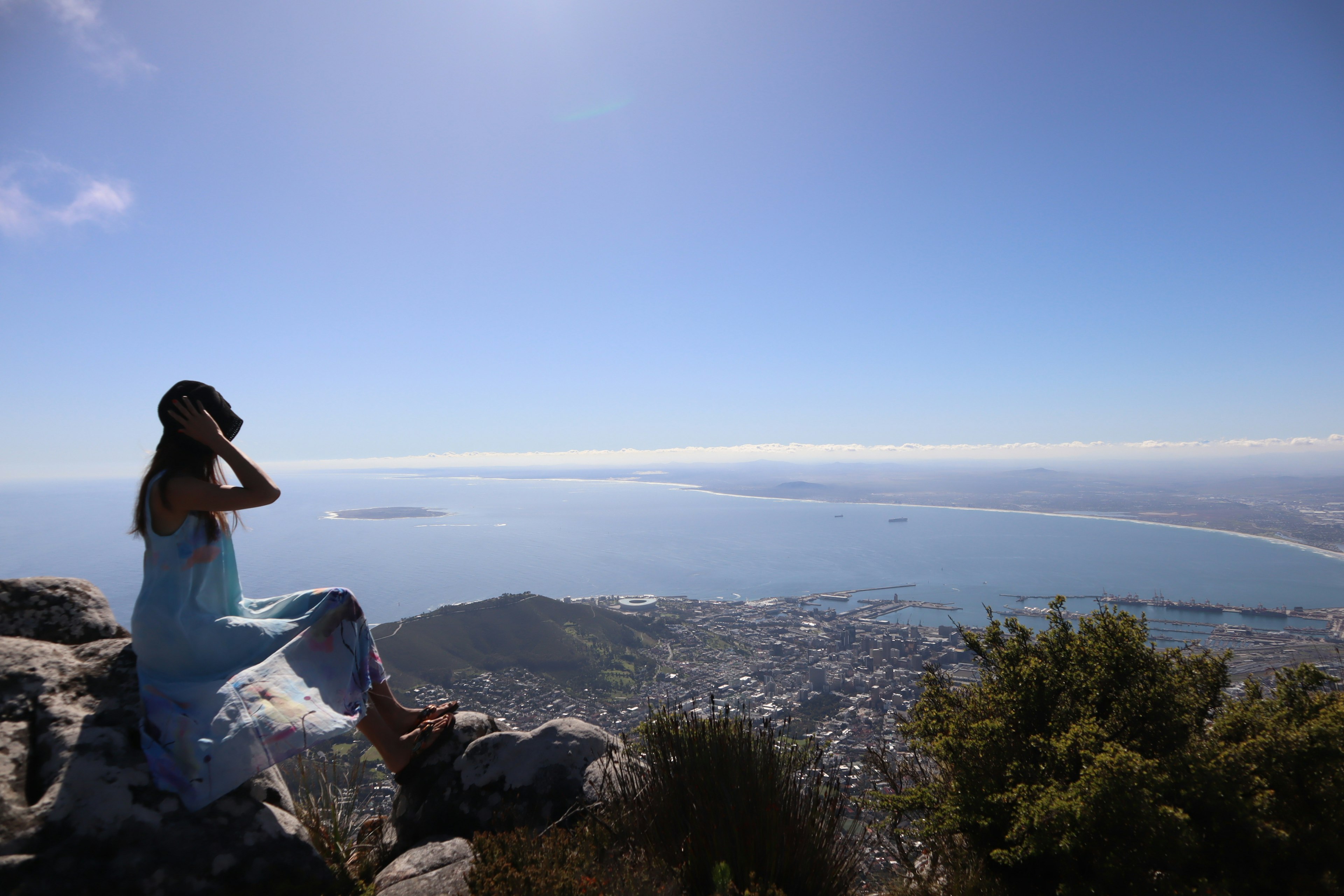 Woman sitting on a rock overlooking the sea and landscape