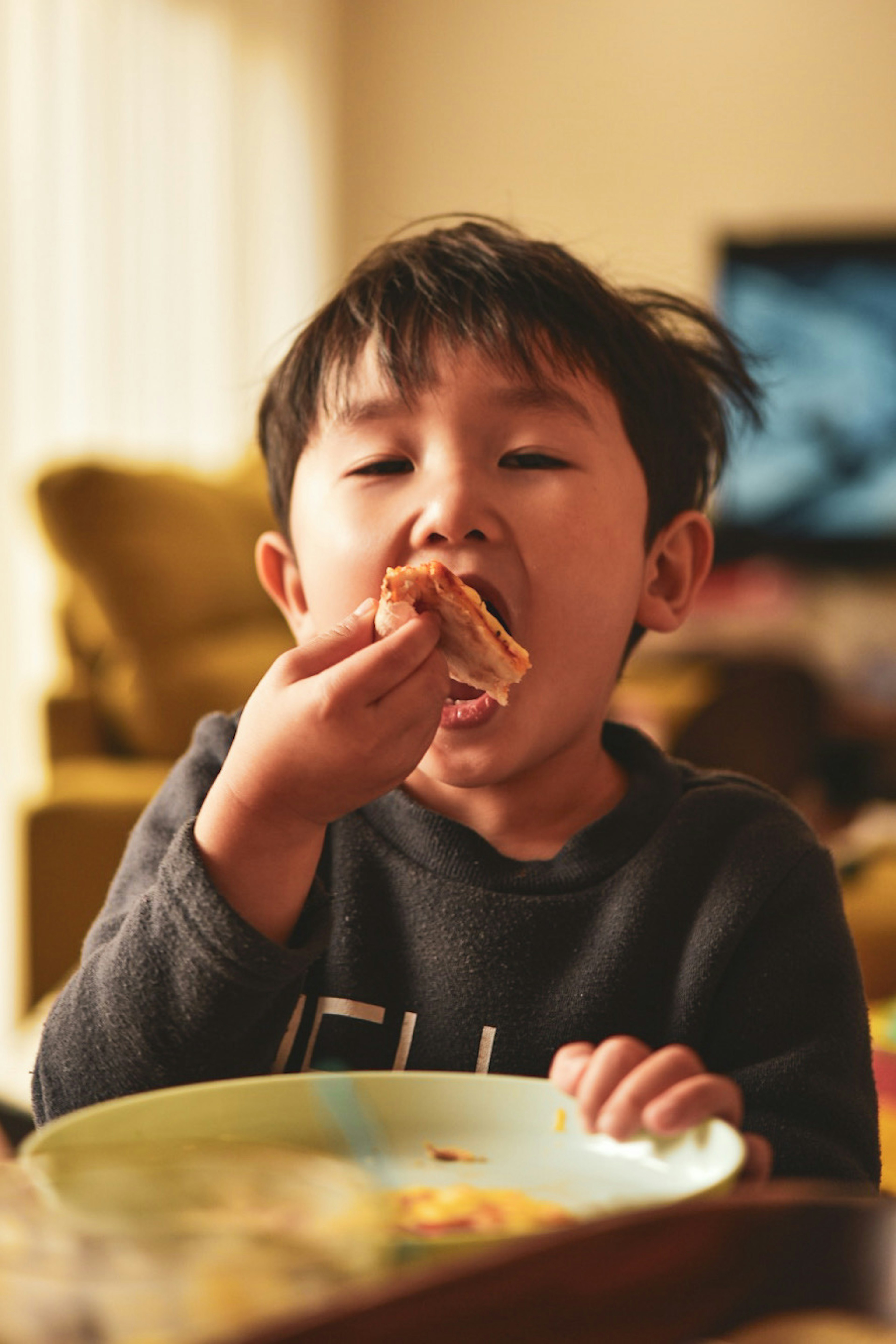 Enfant mangeant dans un bol avec une expression joyeuse