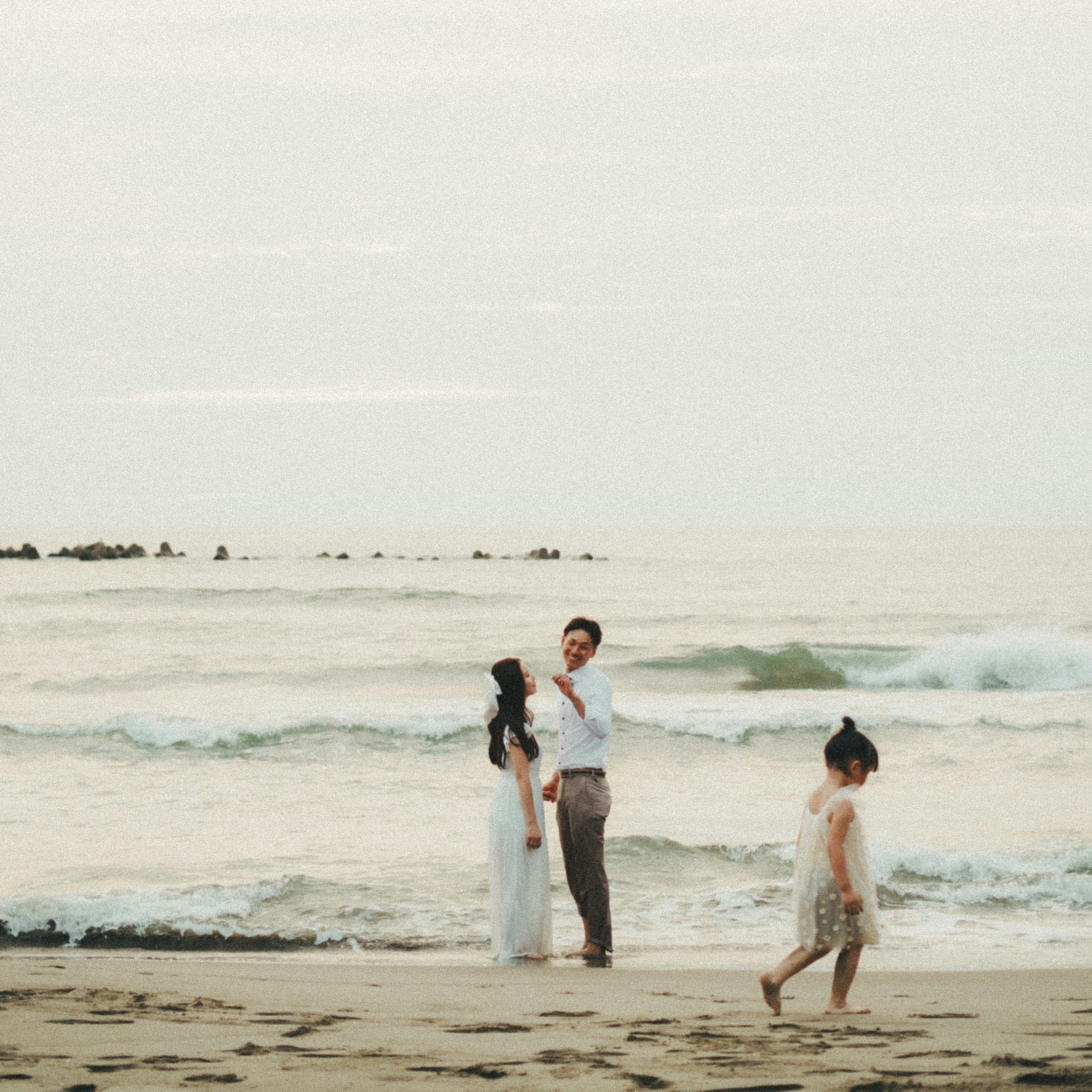 Pareja y niño en la playa con olas suaves