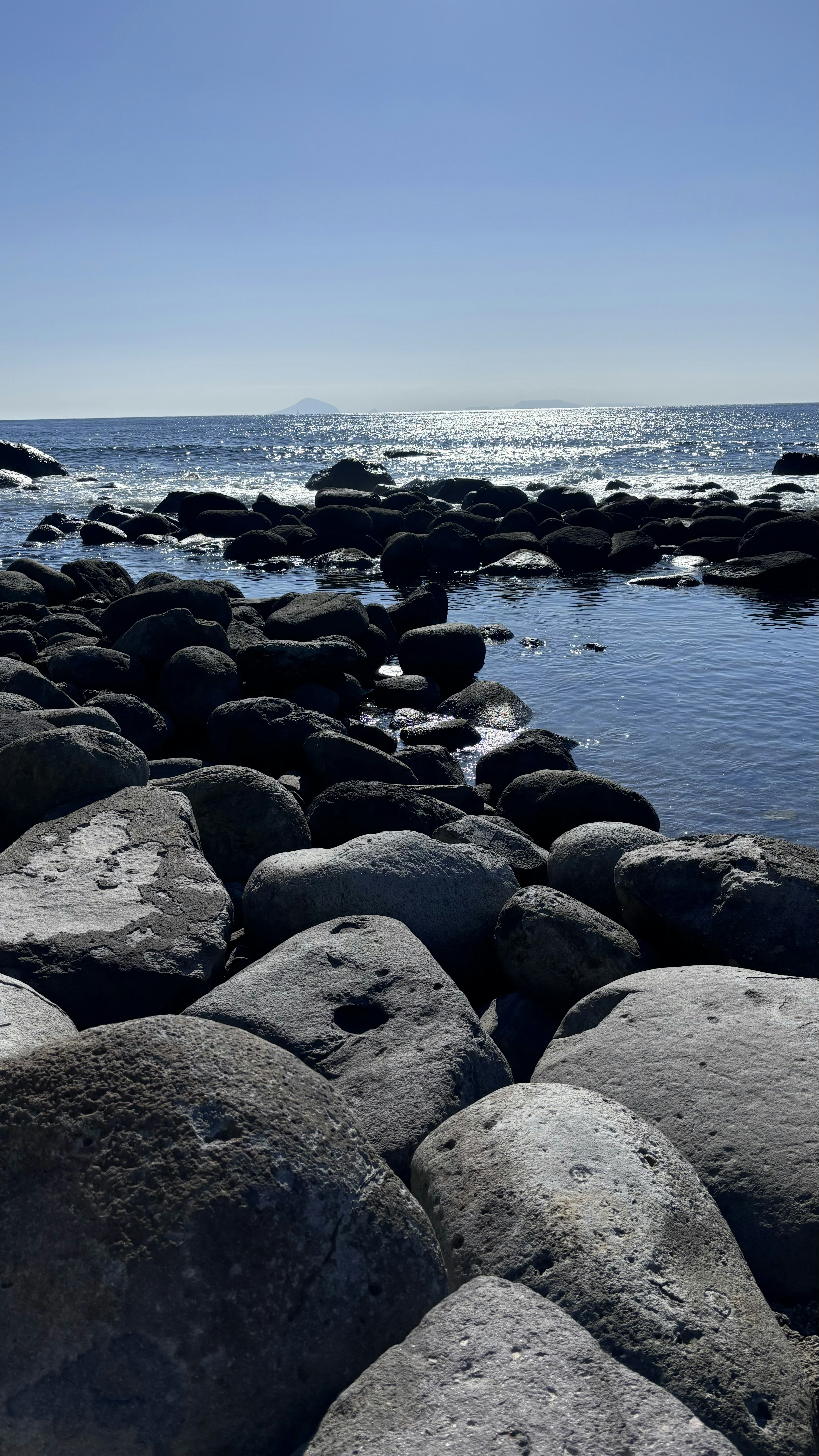 岩石海岸和宁静的海浪与清澈的蓝天