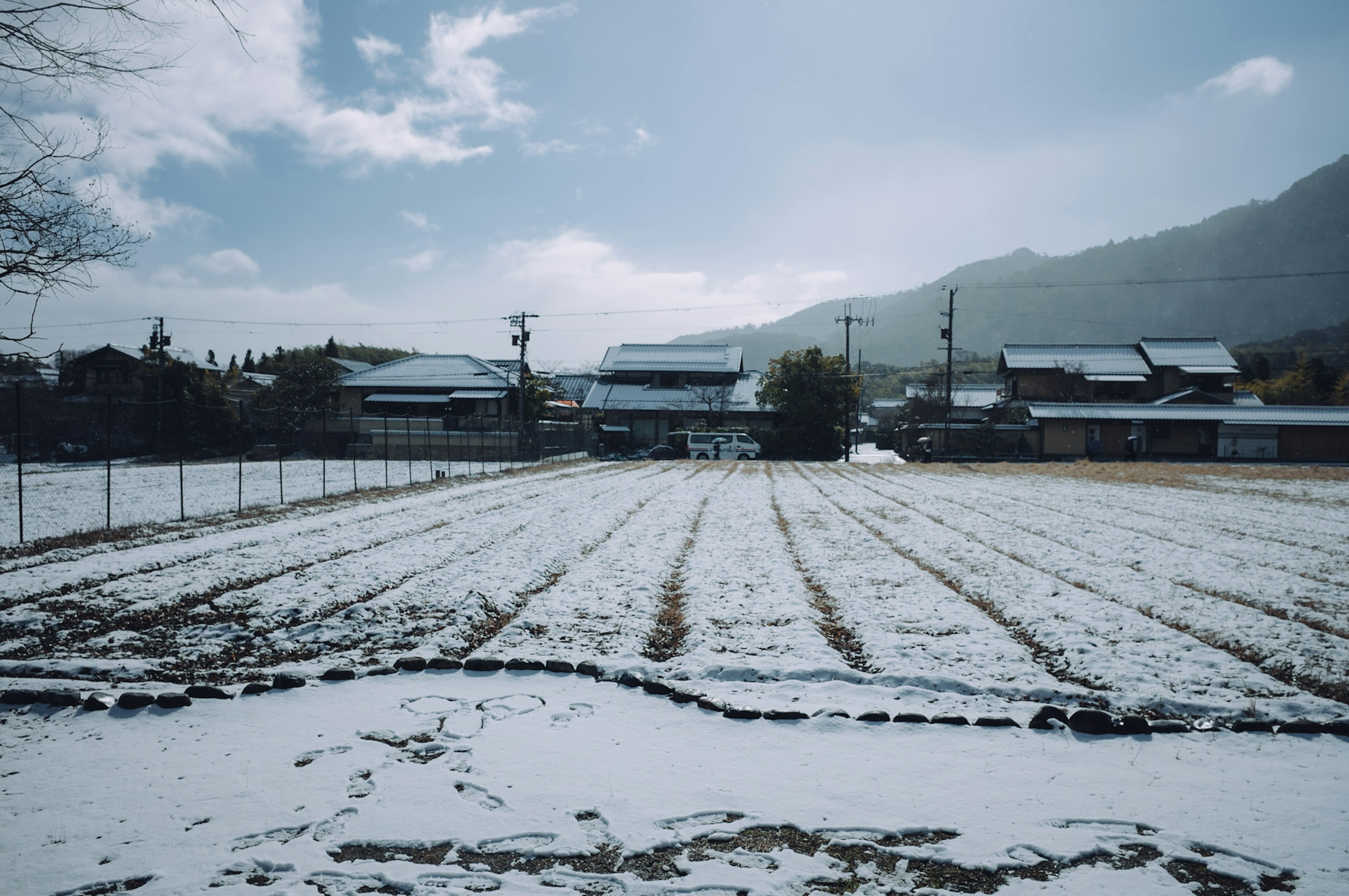 被雪覆蓋的稻田與背景中的房屋和山脈