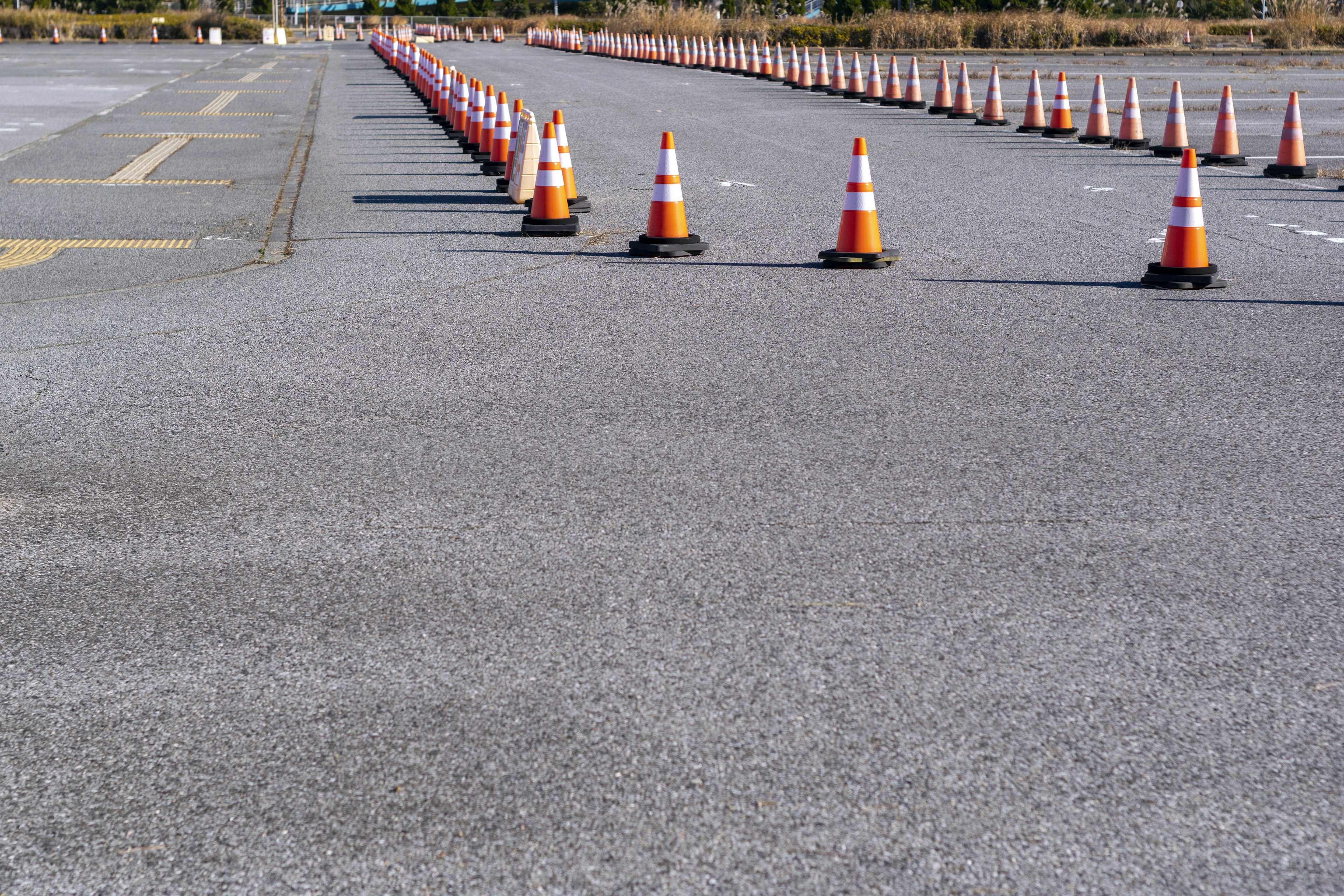 Eine Reihe von orange-weißen Verkehrshütchen, die auf einem Gehweg aufgereiht sind