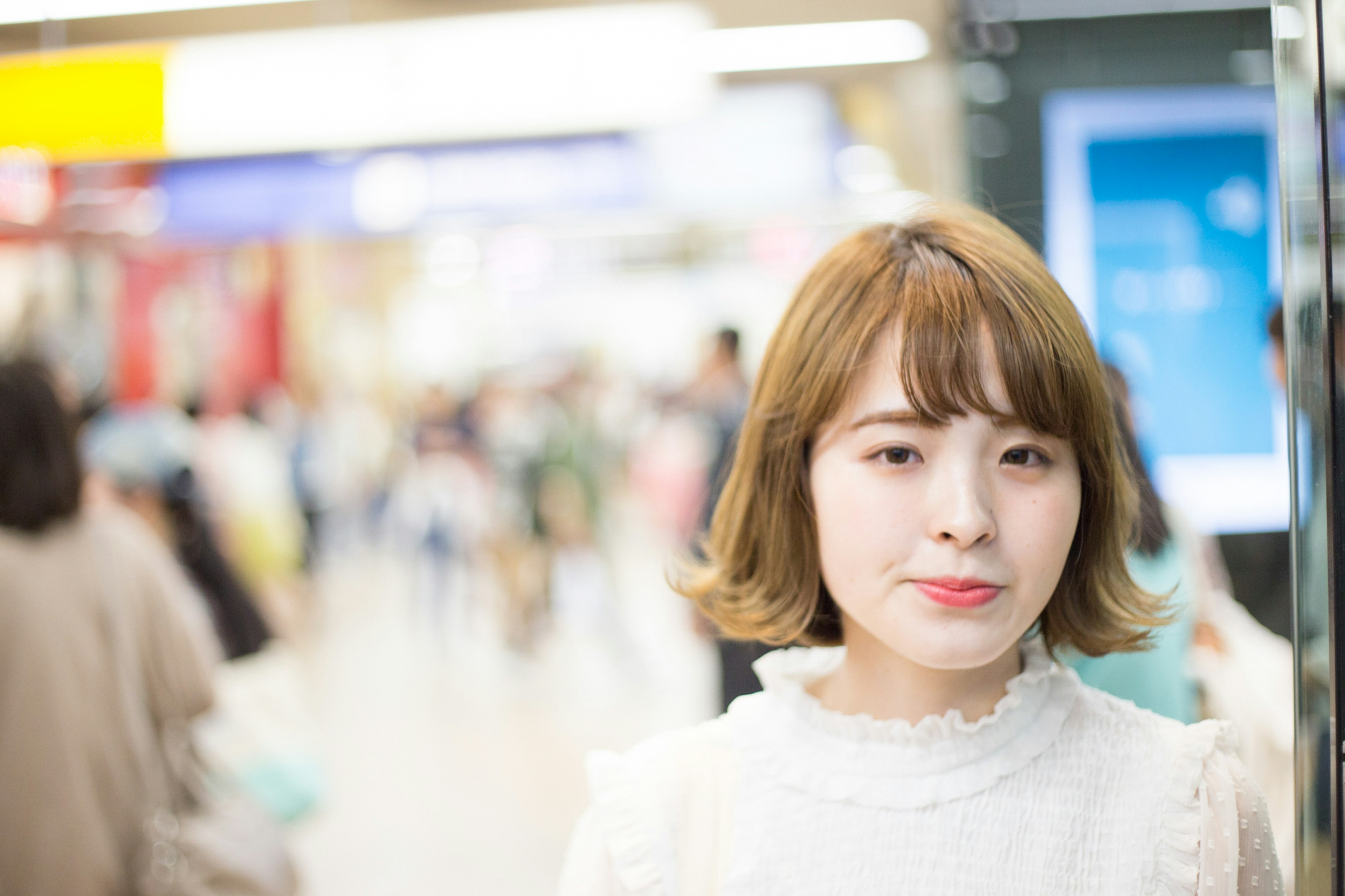 Portrait d'une femme souriante dans une gare avec de nombreuses personnes en arrière-plan