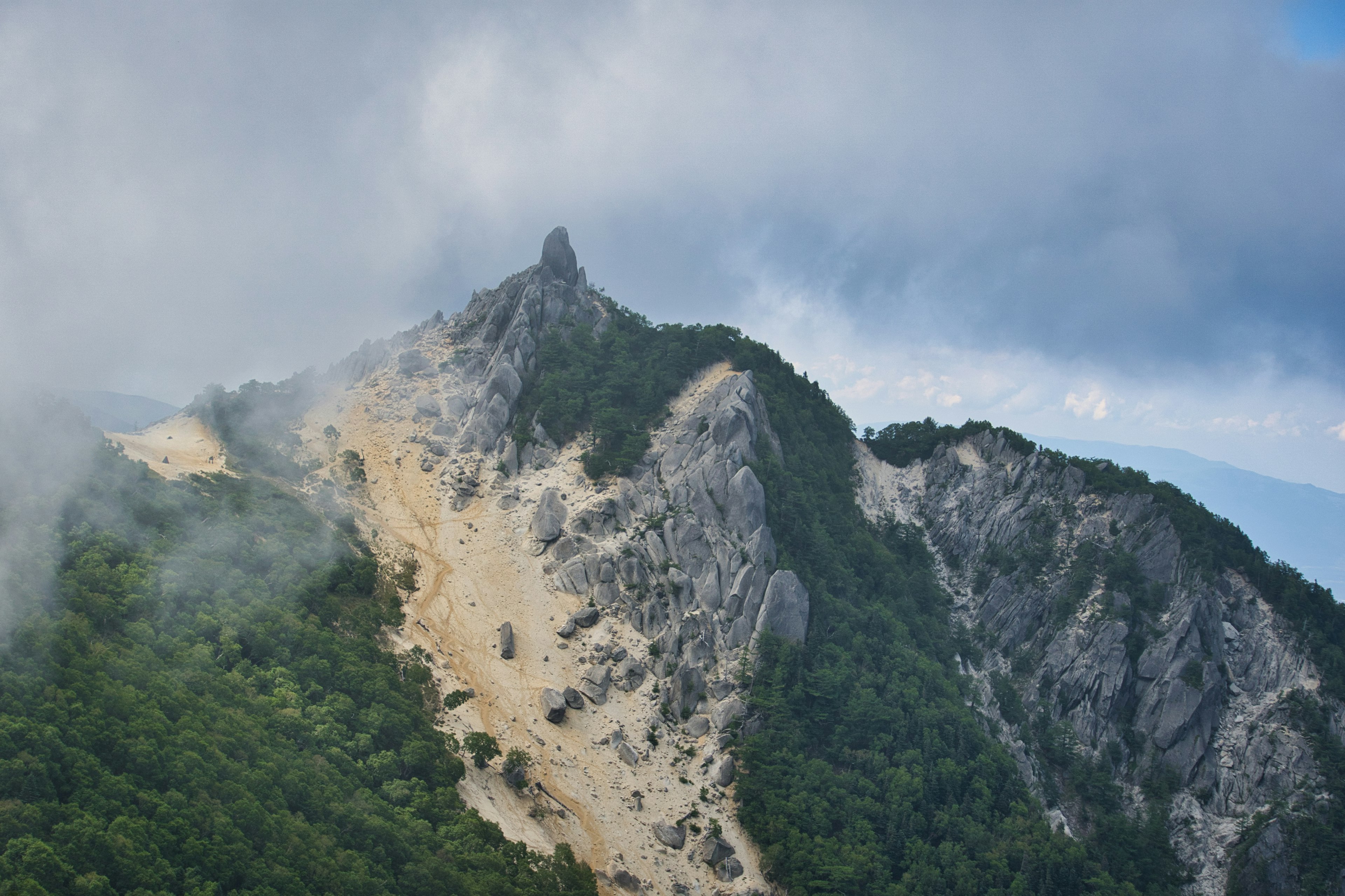 被云雾笼罩的山景，尖锐的岩石山峰和郁郁葱葱的植被